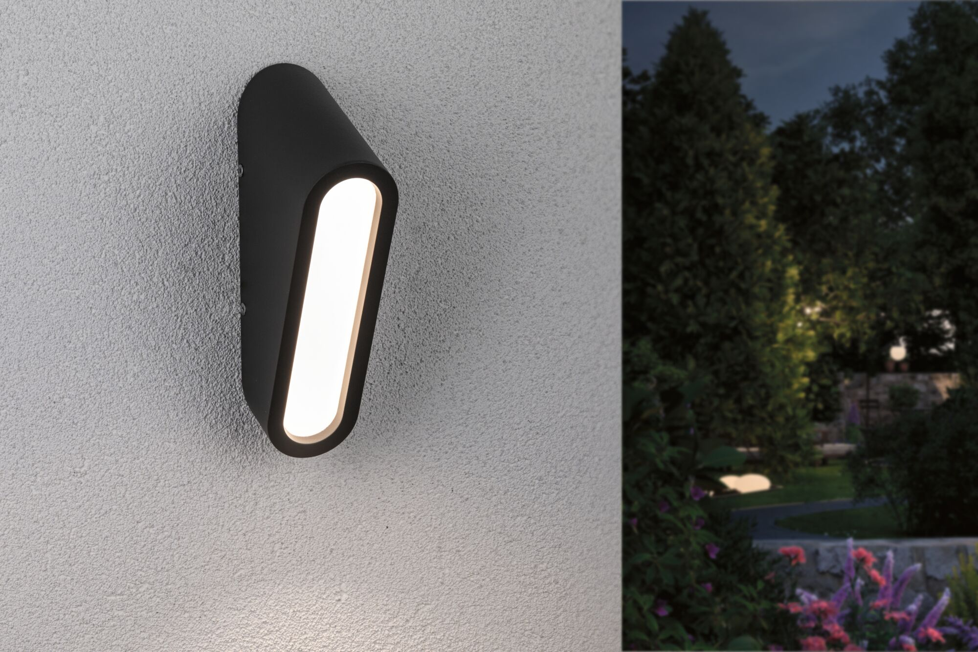 Schwarze Wandleuchte mit hellem Licht an einer strukturierten Wand, neben Bäumen.