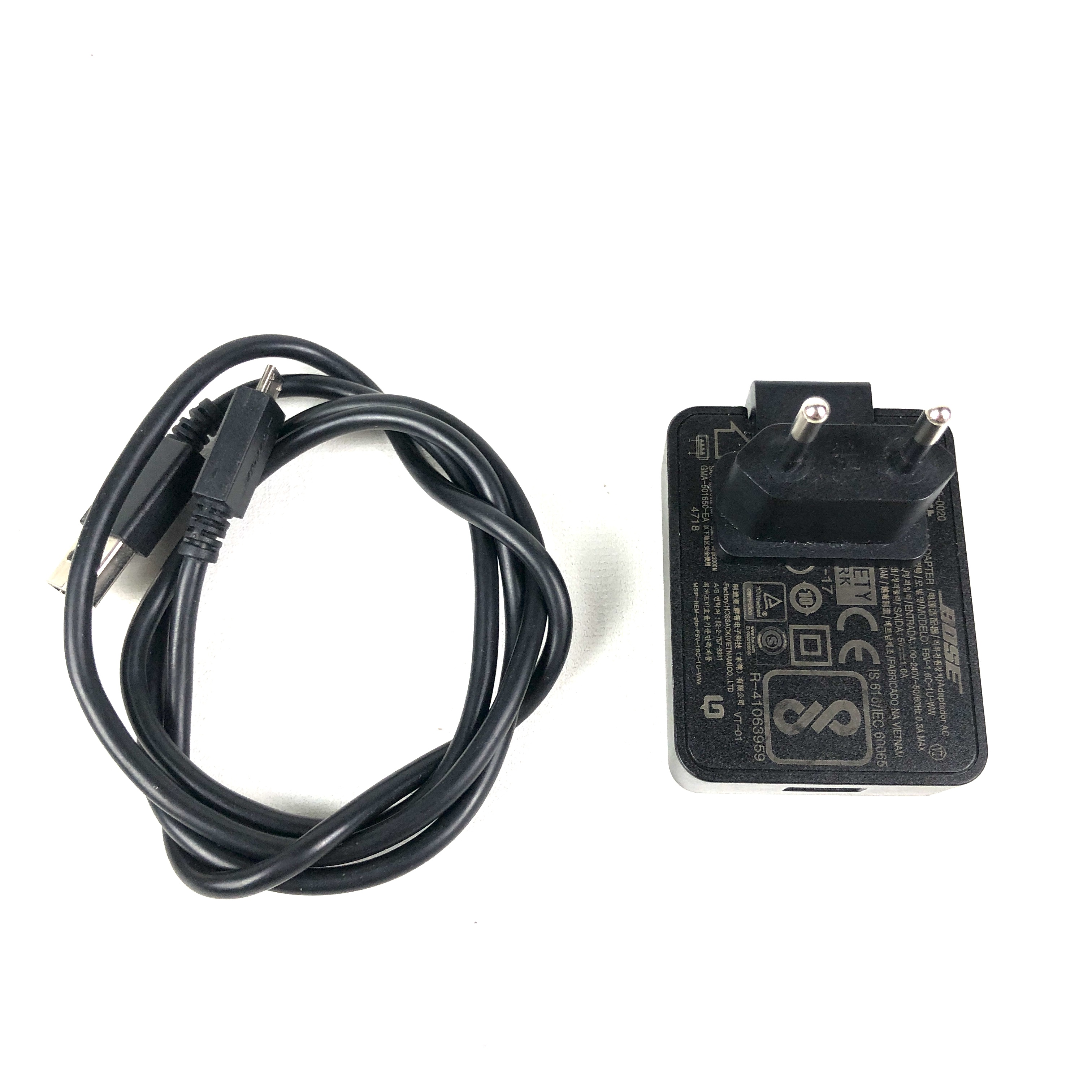 Ein schwarzes USB-Kabel liegt neben einem schwarzen Bose-Netzteil mit EU-Stecker.