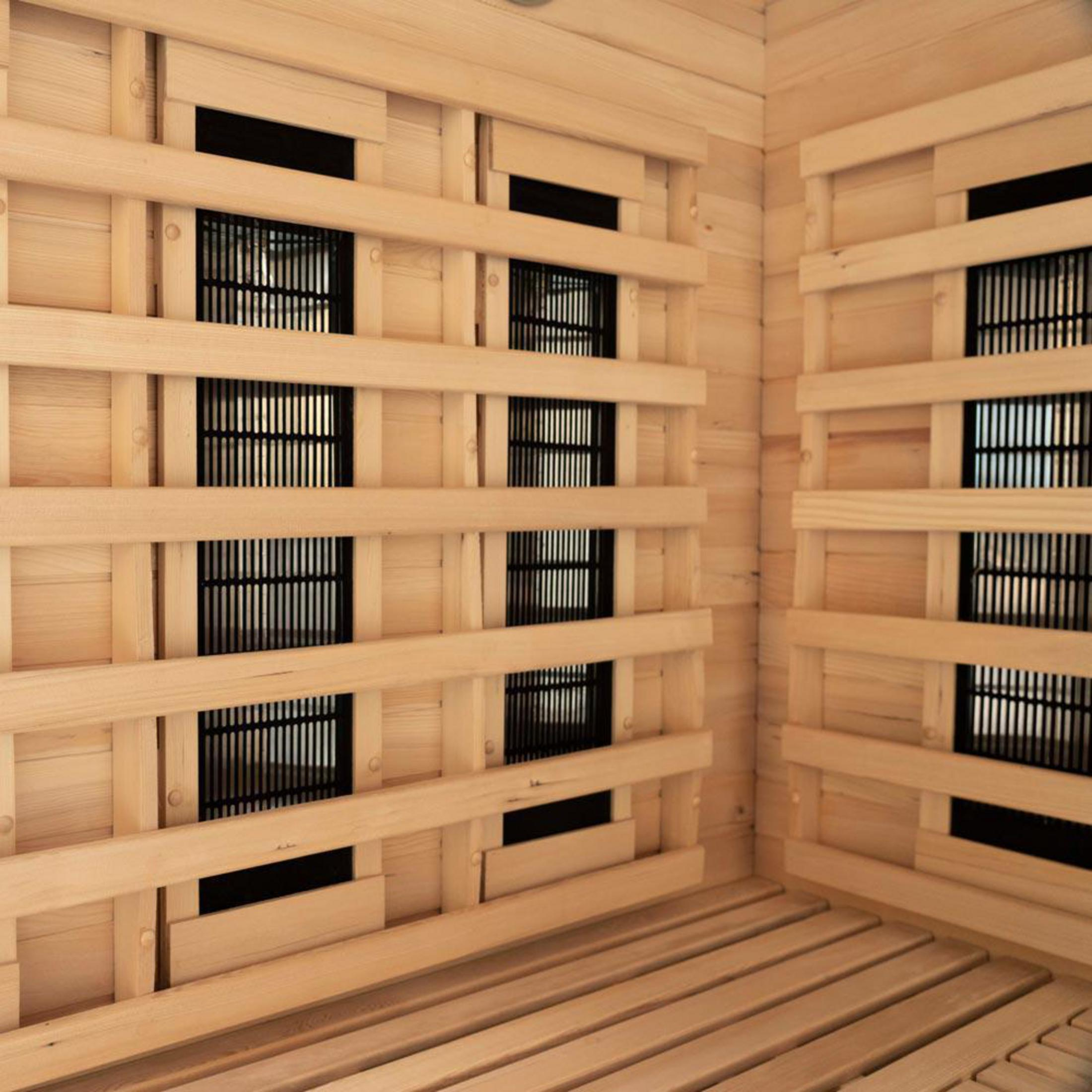 Holzsauna mit Heizkörpern und Sitzbänken. Dunkle Lüftungsgitter.
