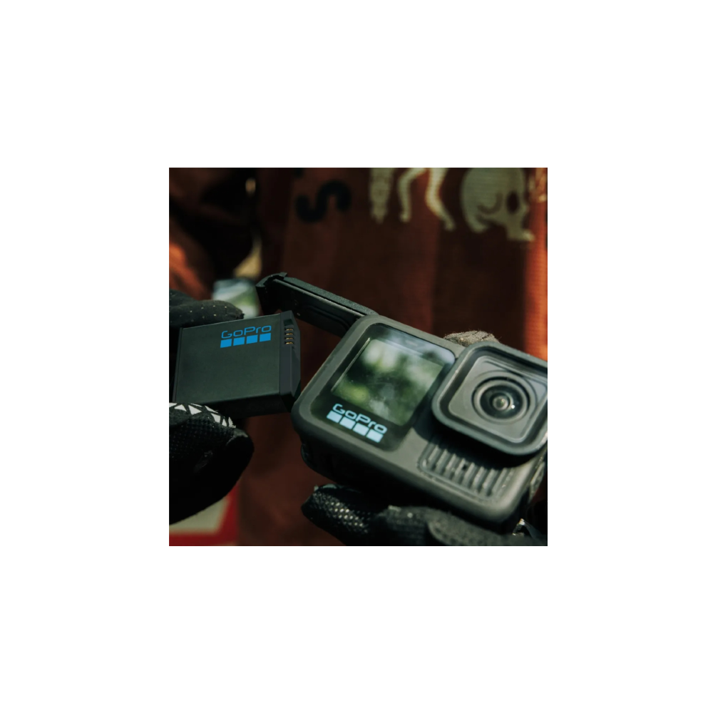 Una mano con guanto nero tiene una fotocamera GoPro e una batteria.