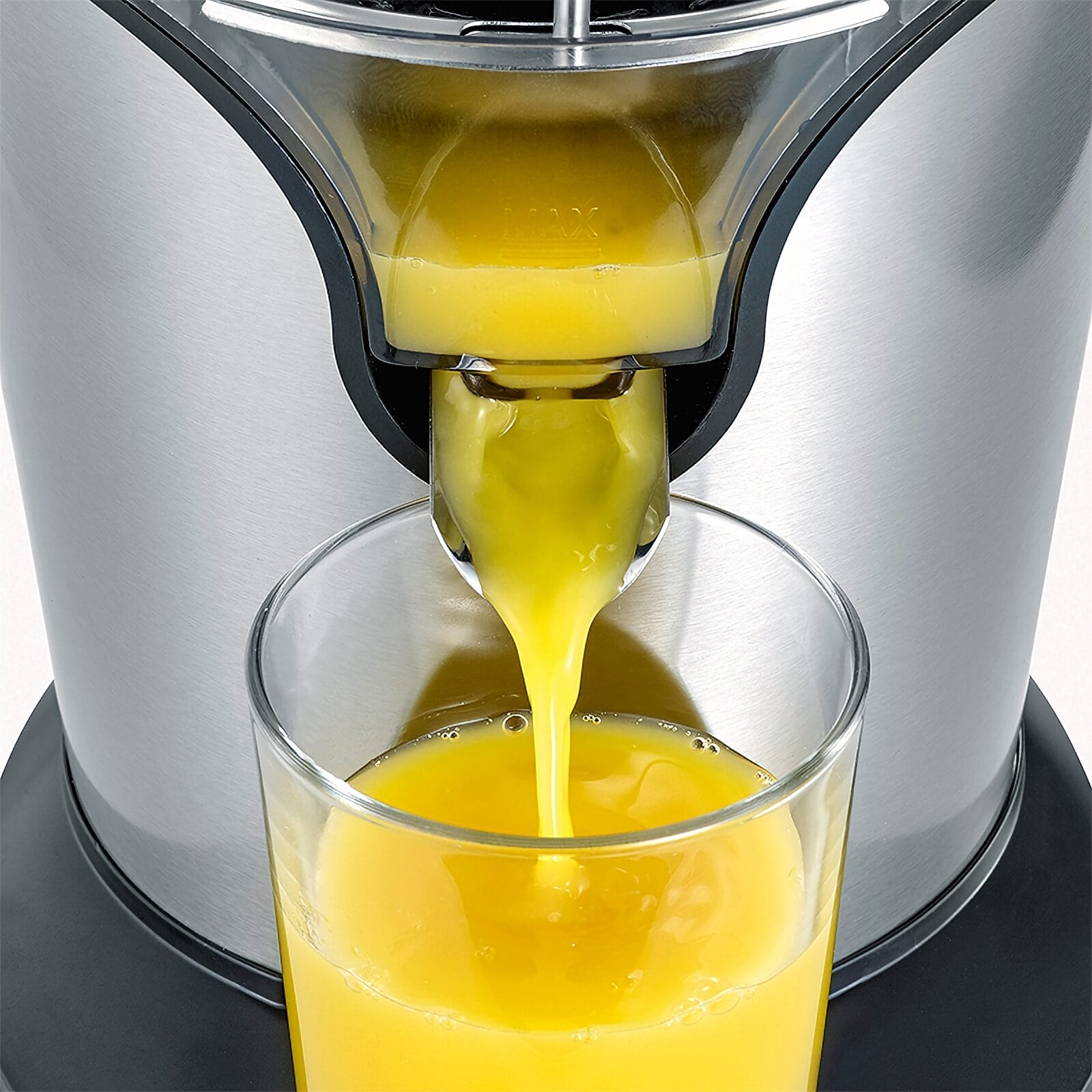 Succo d'arancia appena spremuto che cola da uno spremiagrumi in un bicchiere.