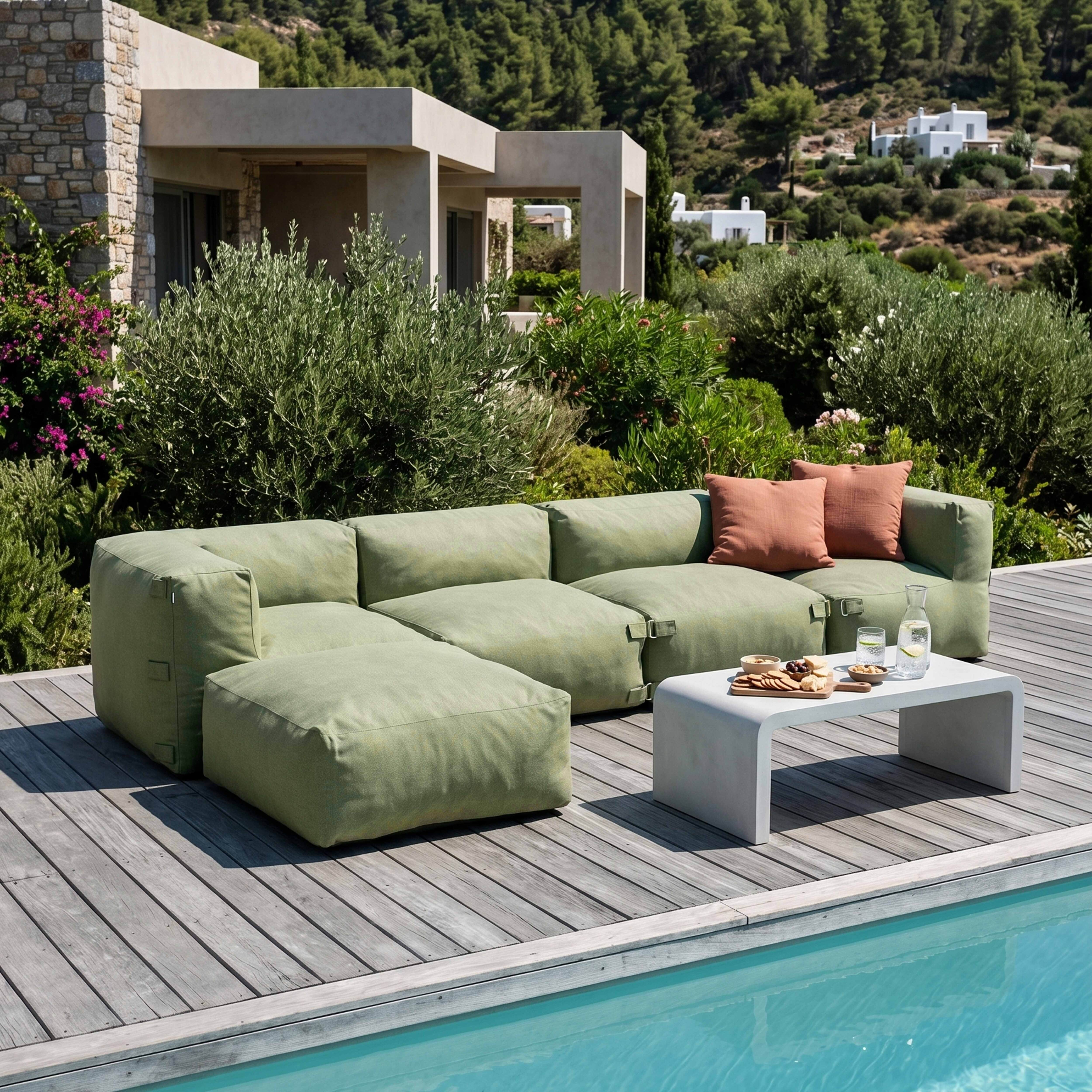 Grünes Modulsofa mit Beistelltisch, Snacks und Getränken auf Holzdeck am Pool.