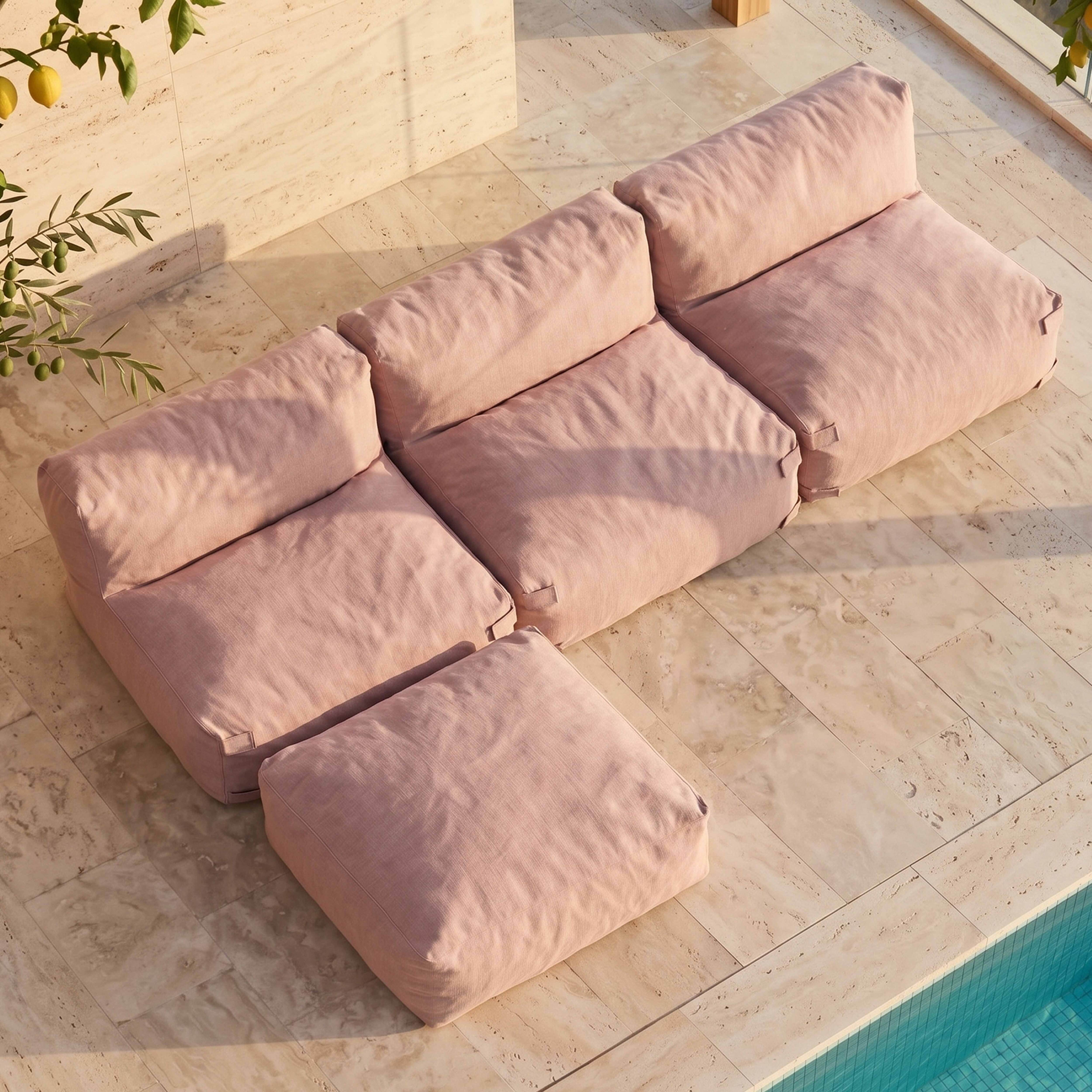 Ein rosa Modulsofa und ein Hocker stehen auf einer gefliesten Terrasse neben einem Pool.