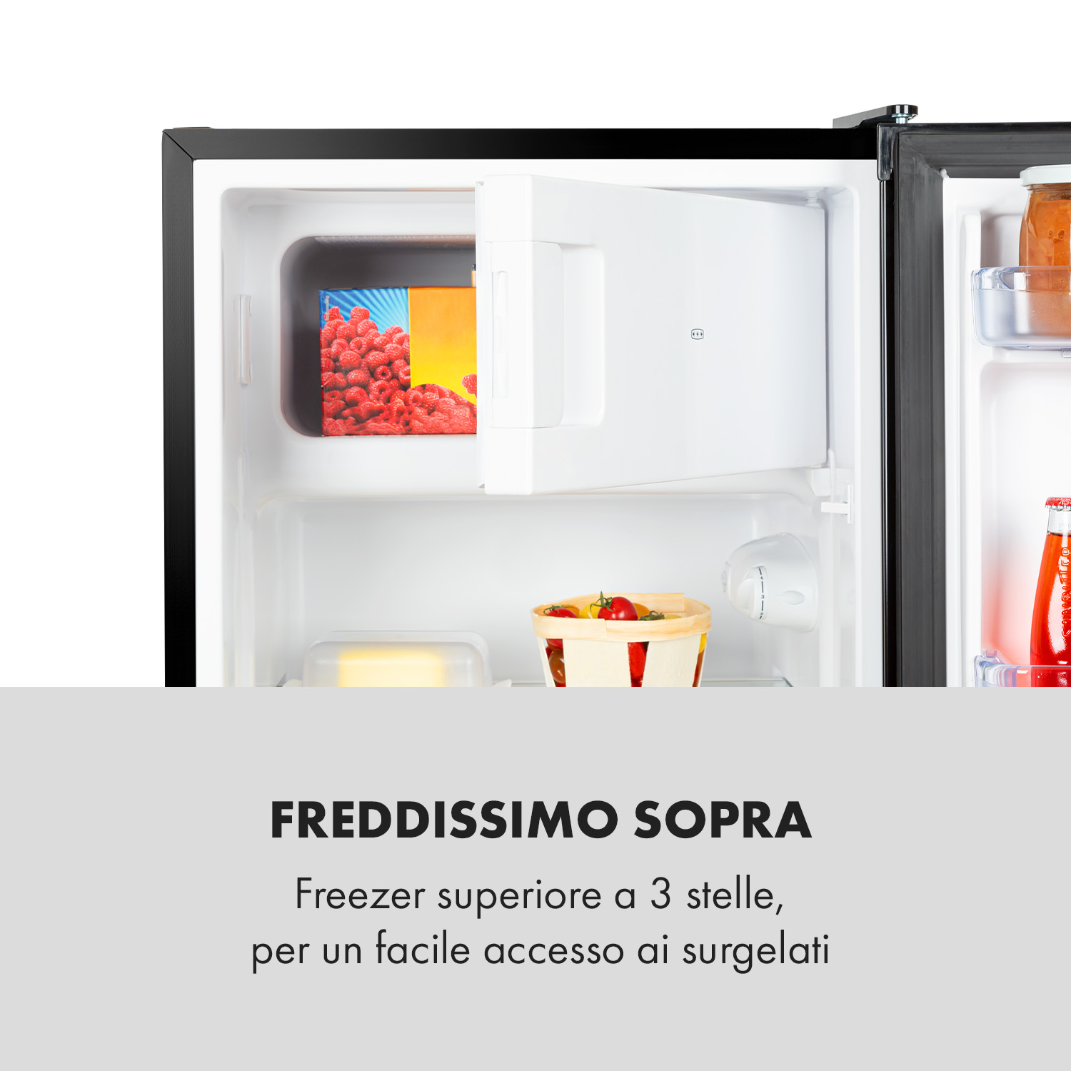 Frigorifero aperto con cassetto congelatore, confezione di frutti di bosco, cestino frutta e bottiglia.