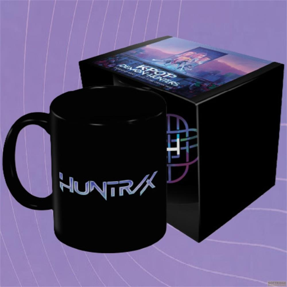 Una taza negra con logo 'HUNTRX' junto a una caja negra de K-pop Demon Hunters.