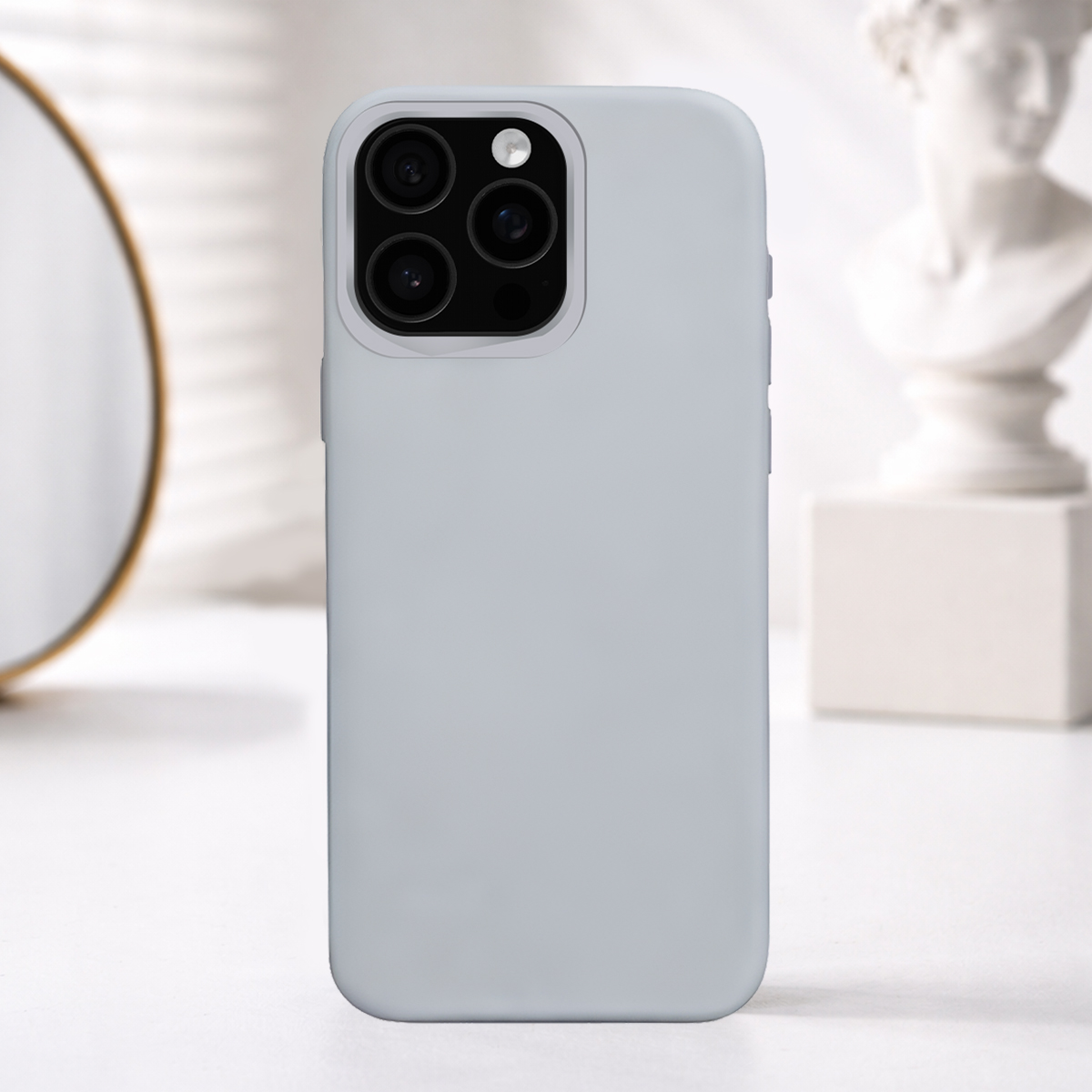 Custodia per telefono grigio chiaro con tripla fotocamera, sfondo sfocato.