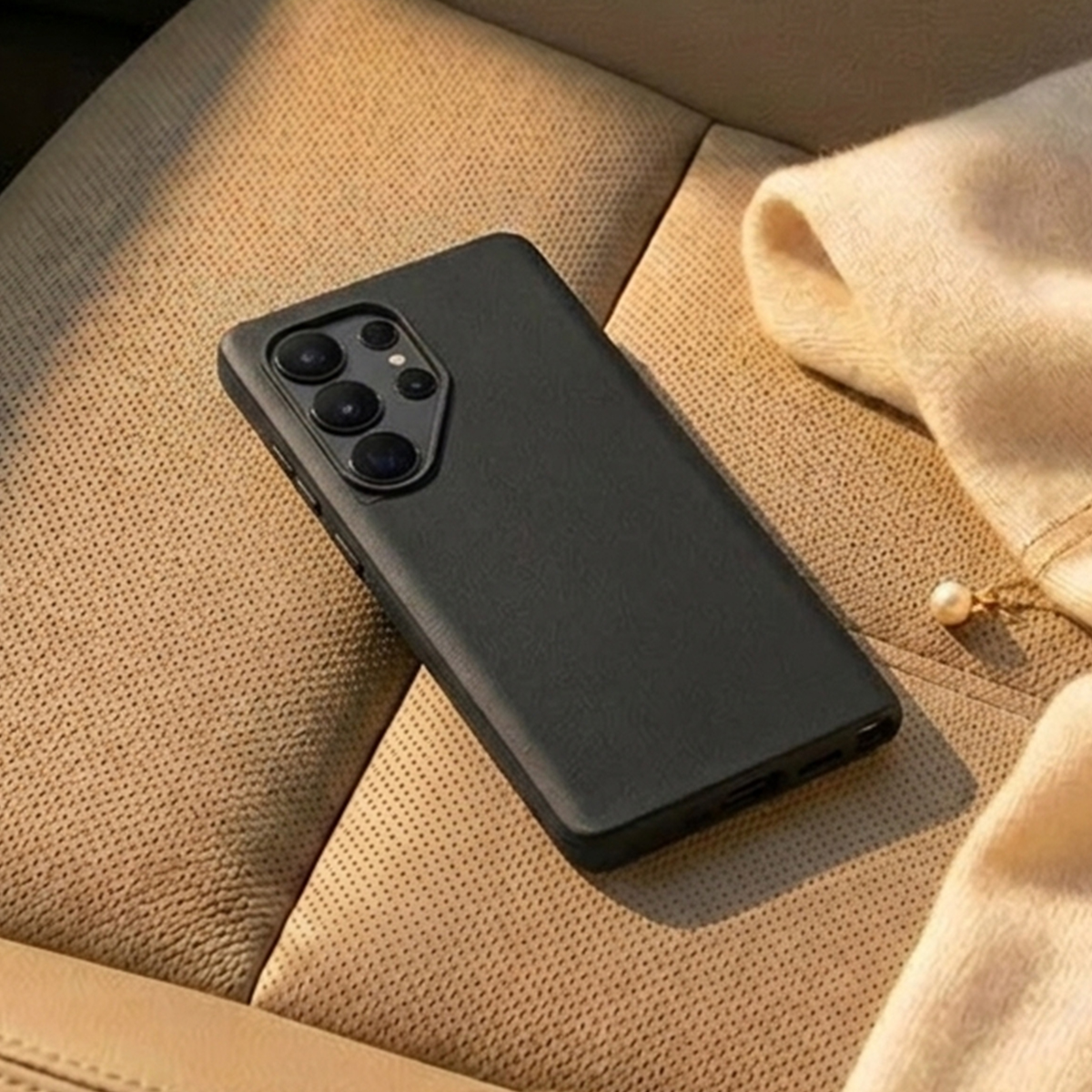 Una custodia nera per telefono con più fotocamere poggia su una superficie beige testurizzata.
