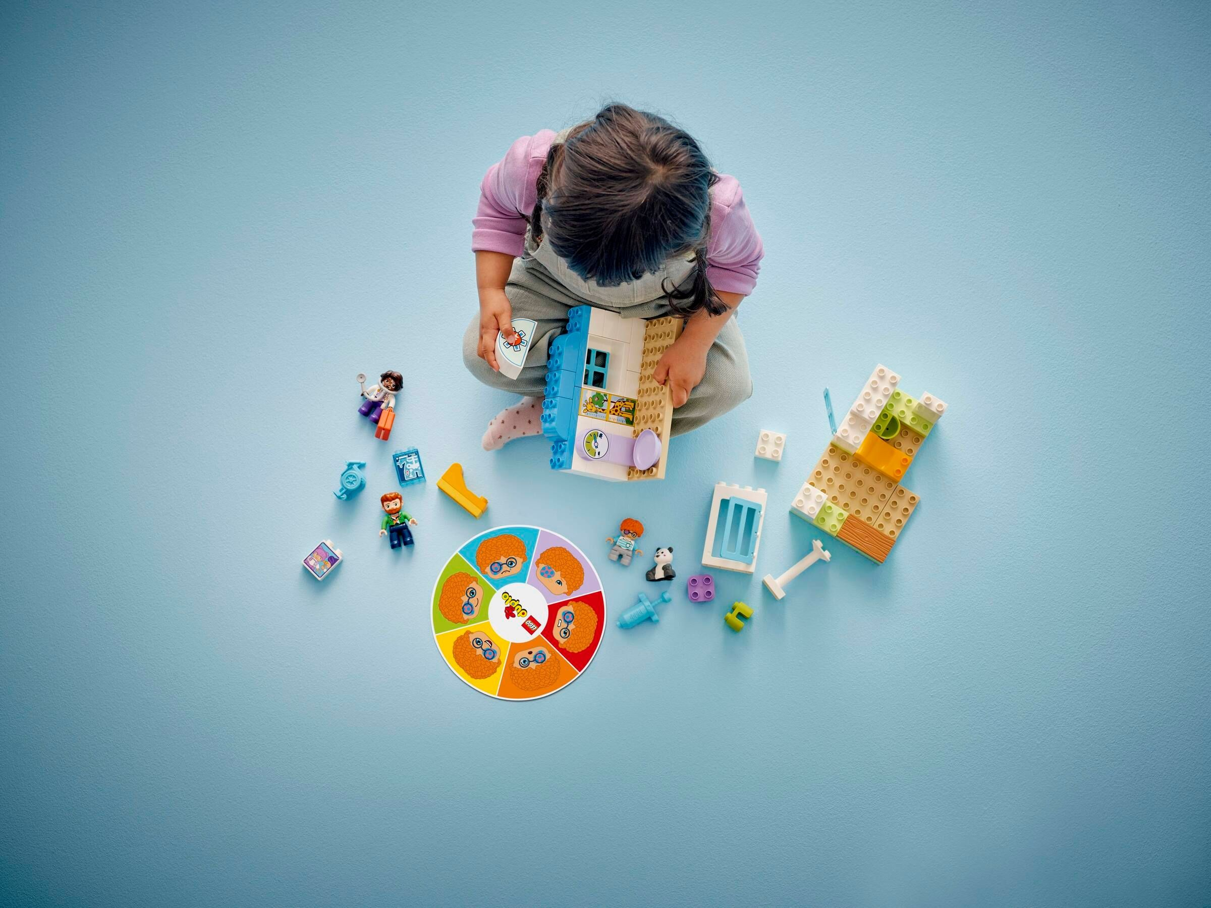 Ein Kind spielt mit bunten Lego-Bausteinen und Figuren auf blauem Hintergrund.