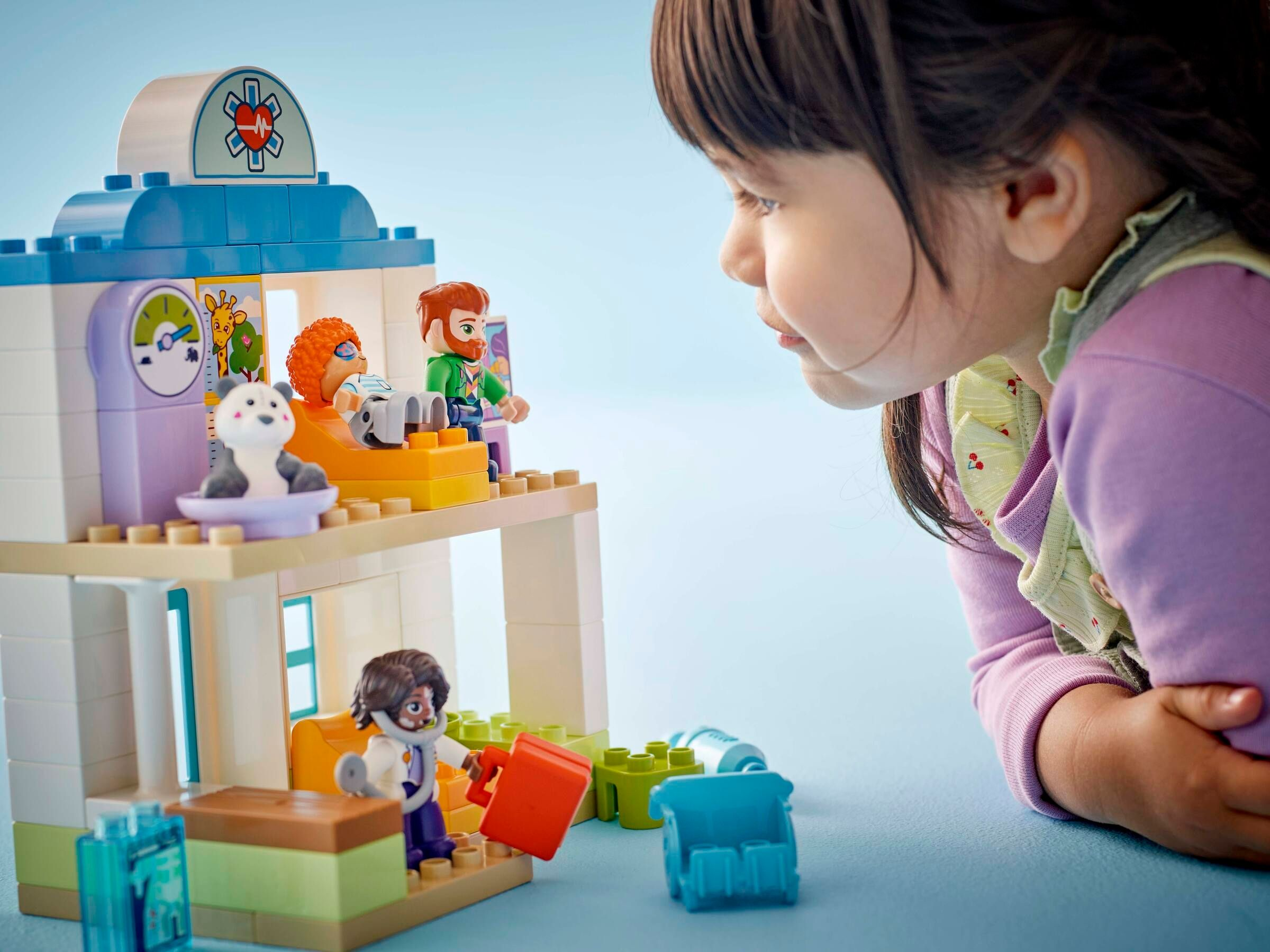 Ein Kind spielt mit einem LEGO-Krankenhaus-Spielzeug mit Figuren und Zubehör.