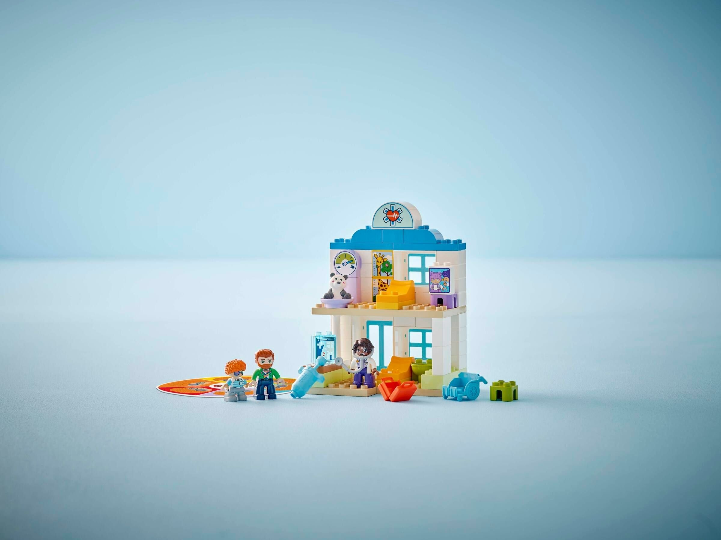 Ein Lego-Tierarztset mit Figuren, einem Gebäude und Zubehör auf blauem Hintergrund.