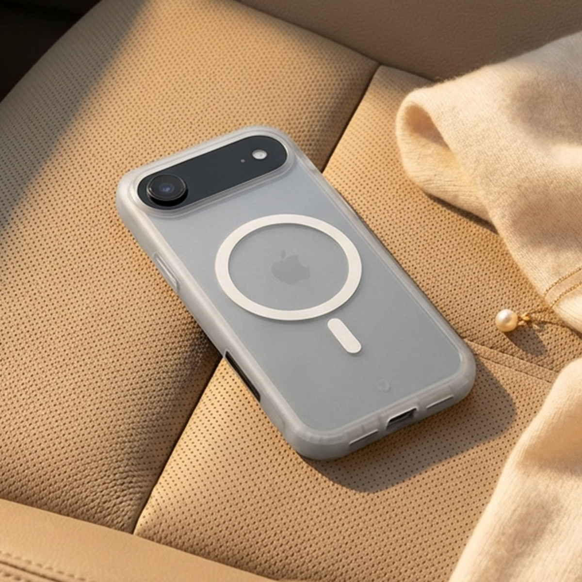 Eine durchsichtige Handyhülle mit weißem MagSafe-Ring und Apple-Logo auf einem hellbraunen Ledersitz.