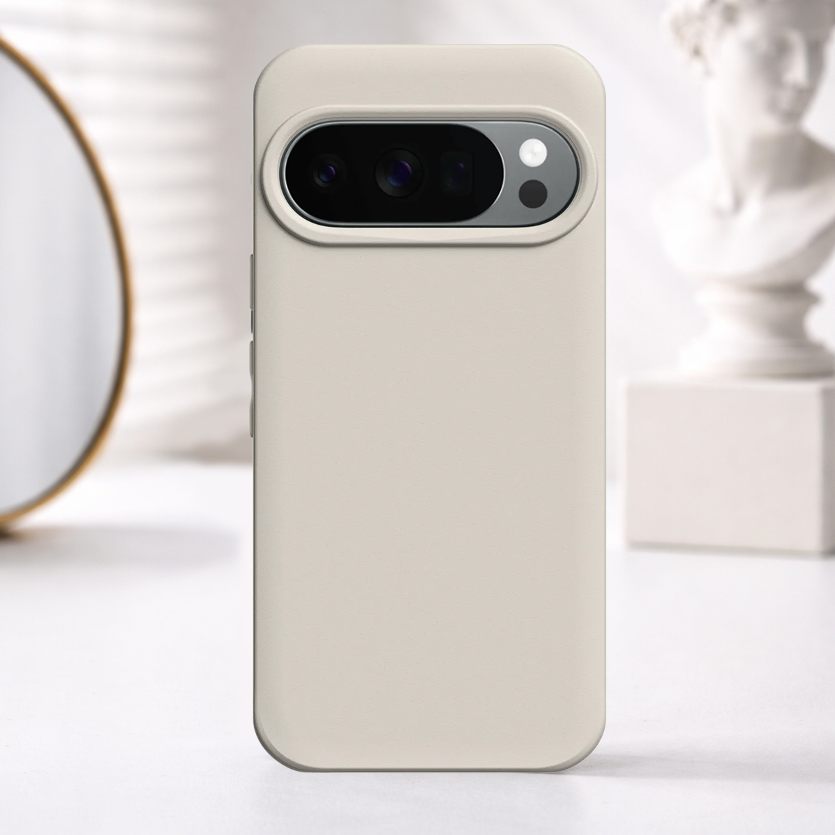 Una custodia per telefono beige con blocco fotocamera su un tavolo, con specchio e busto.