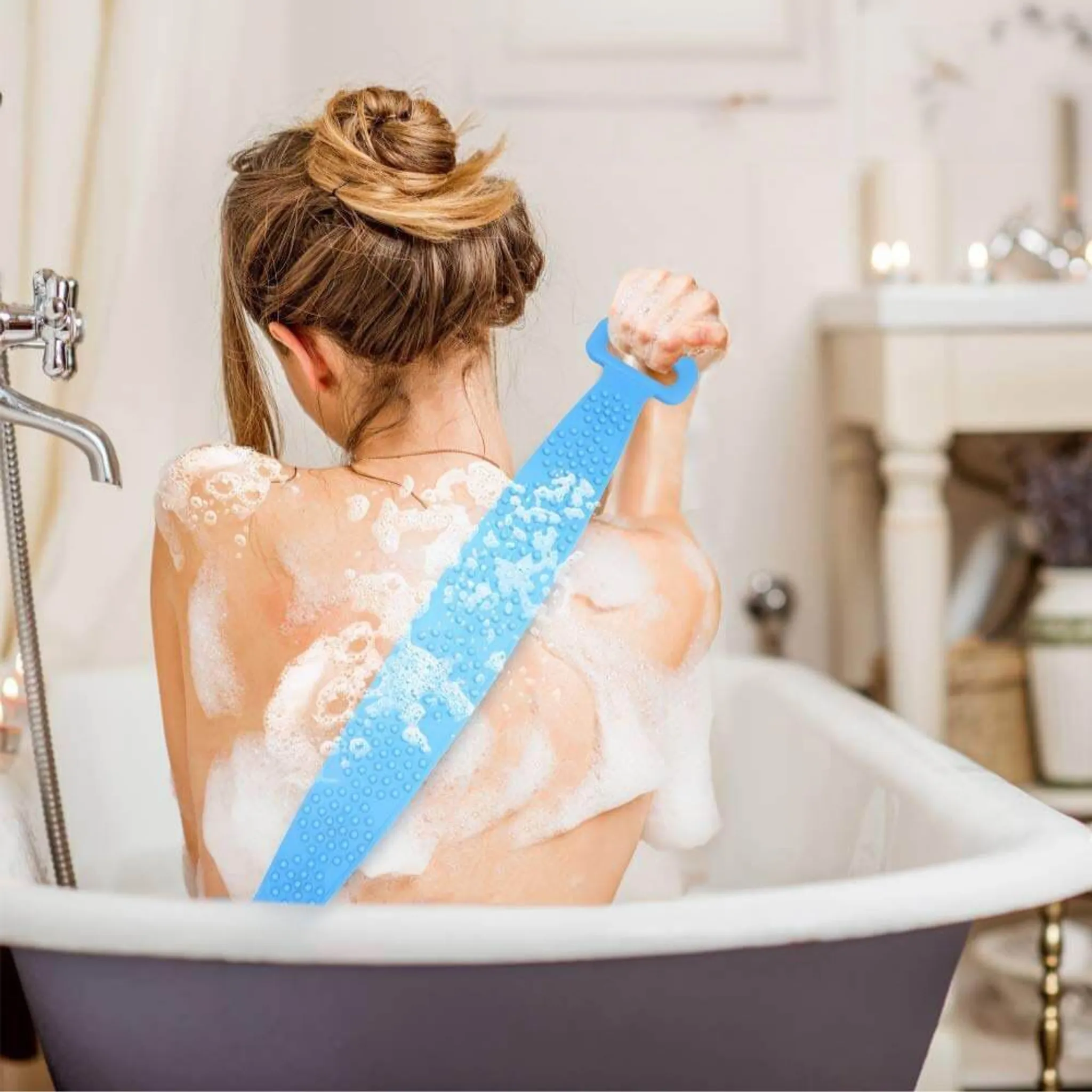 Eine Frau mit hochgesteckten Haaren sitzt in einer Badewanne und schrubbt ihren Rücken mit einem blauen Silikon-Duschgurt.