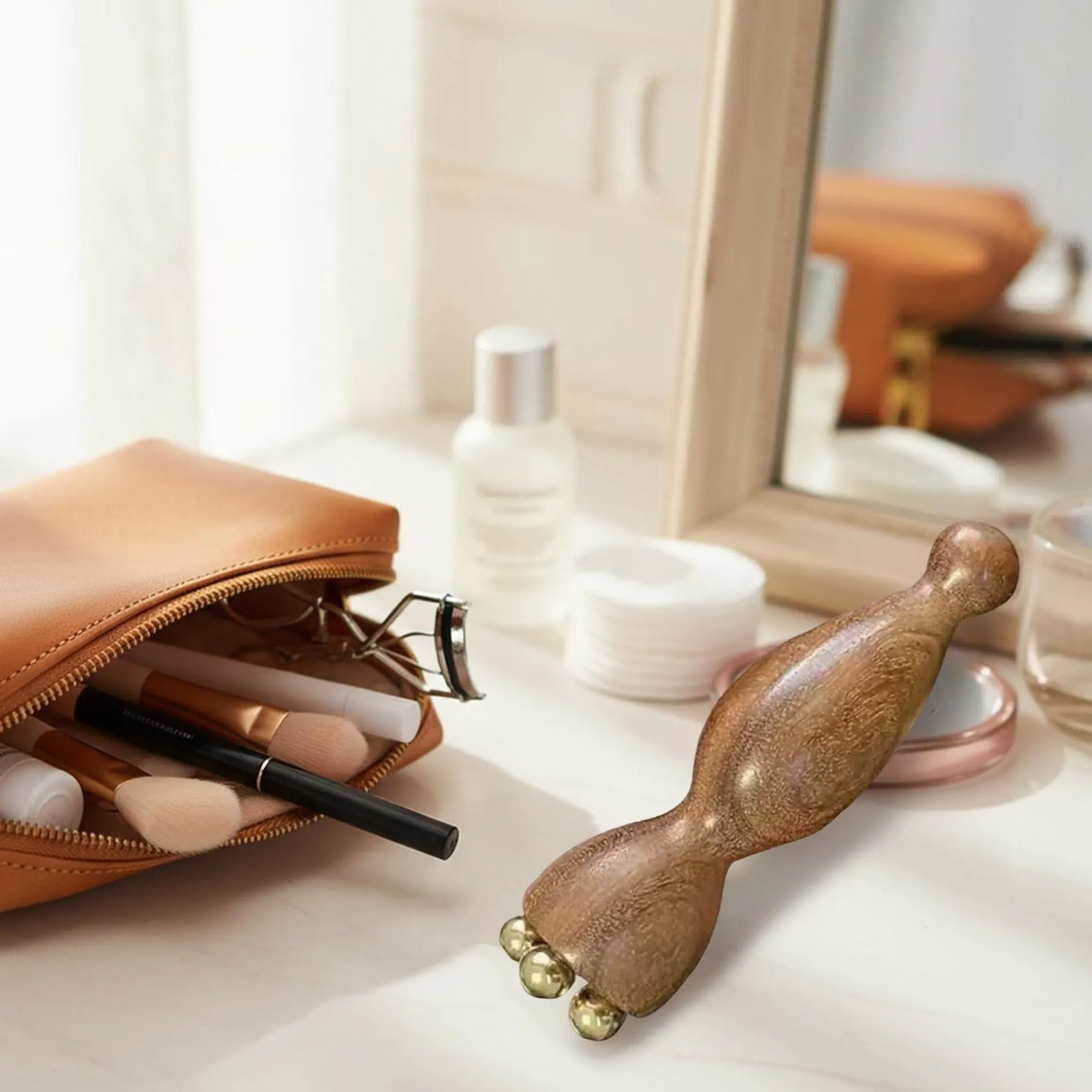 Ein Holzmassagegerät mit Kugeln liegt neben einer offenen Kosmetiktasche mit Pinseln.