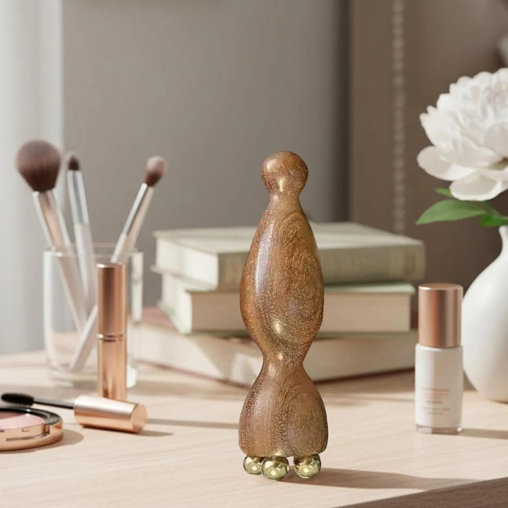 Ein hölzerner Körperpflege-Roller mit goldenen Kugeln steht auf einem Tisch neben Kosmetik.