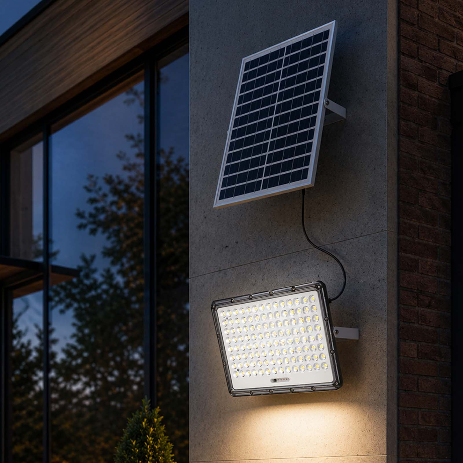 Ein Solarpanel und ein heller LED-Strahler an einer Hauswand bei Nacht.