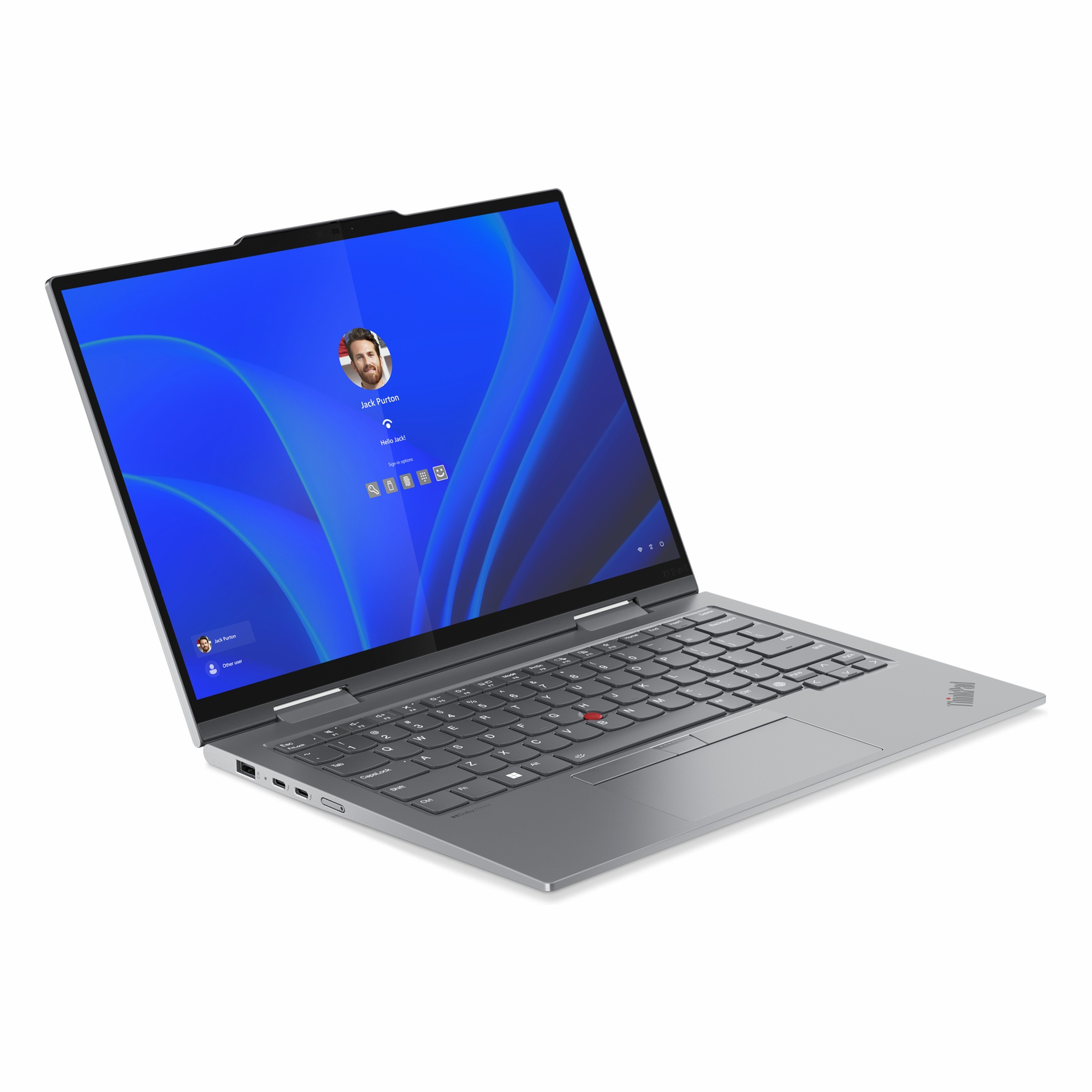 Gümüş renkli bir dizüstü bilgisayar açık, mavi bir Windows oturum açma ekranı gösteriyor.