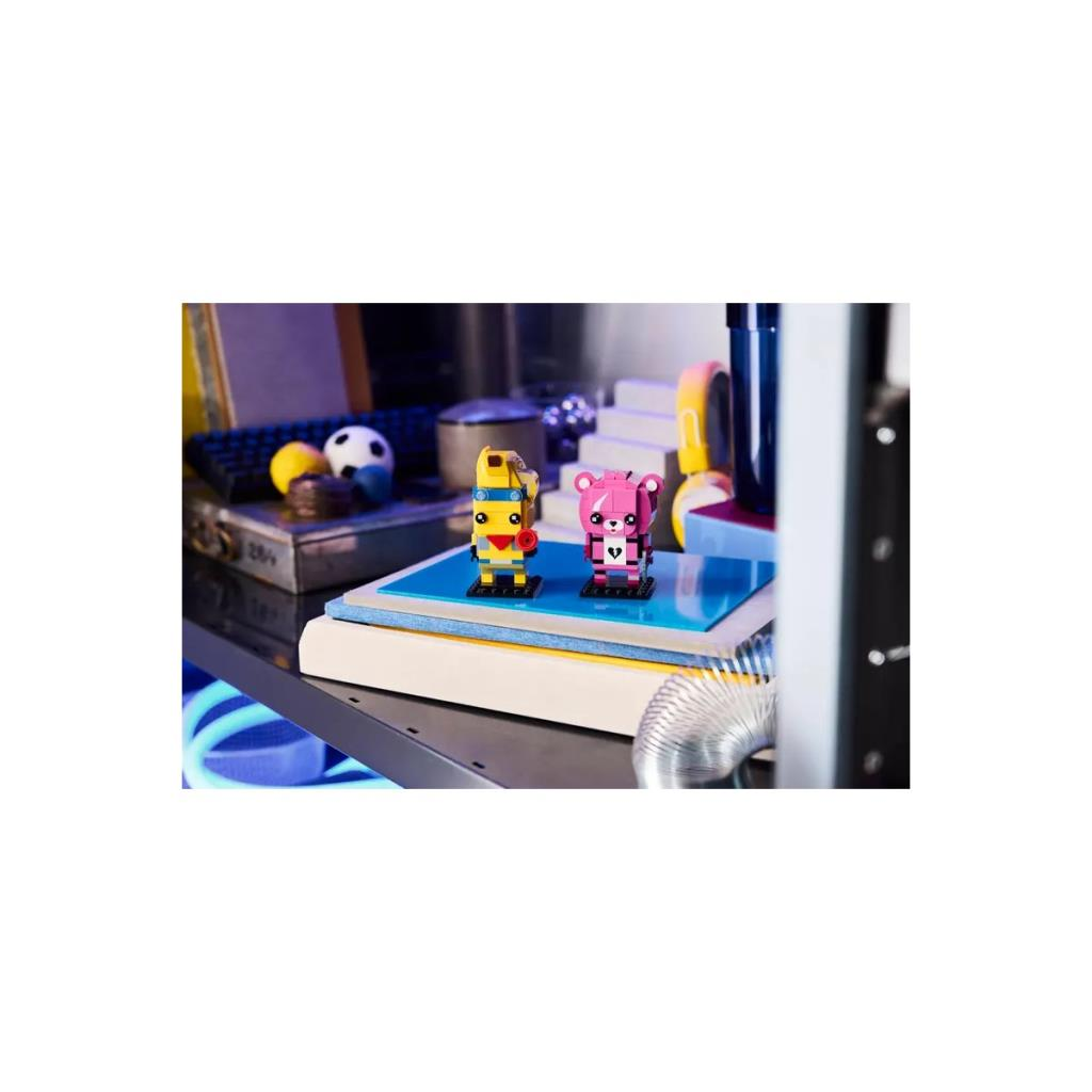 Figure Lego robot giallo e orso rosa su superficie blu con slinky.
