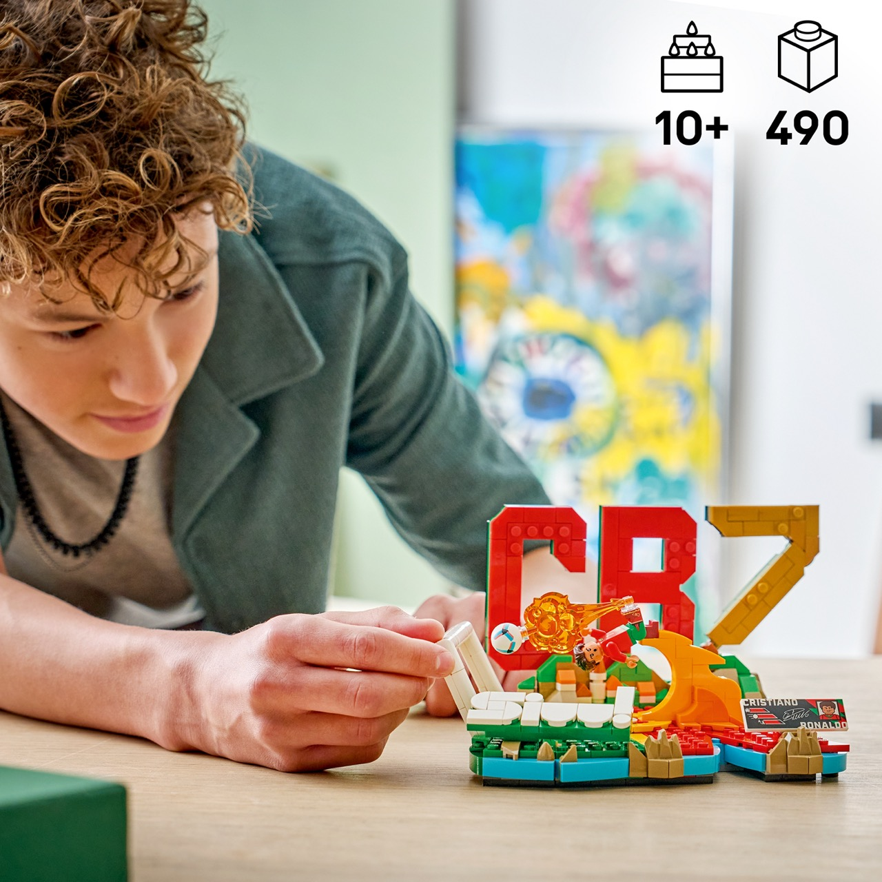 Chłopiec buduje kolorowy zestaw LEGO CR7 z piłkarzem kopiącym piłkę.