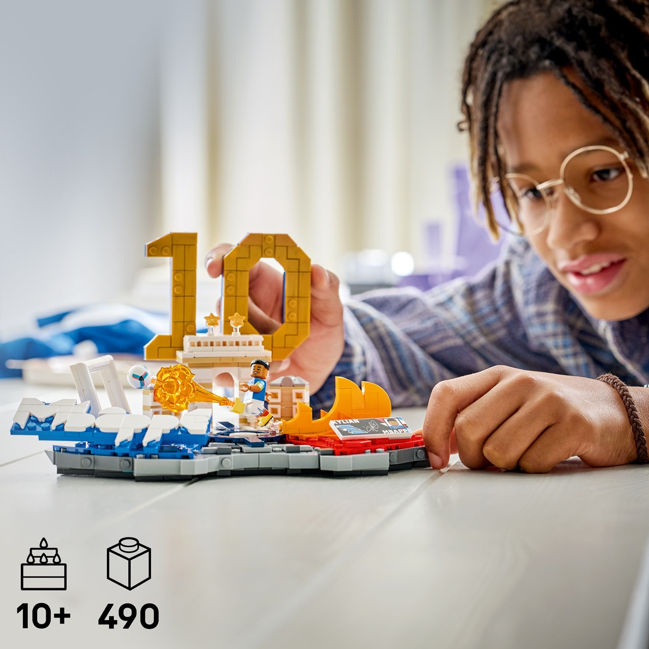 Bir çocuk, altın rengi 10 rakamı ve futbol temalı öğeler içeren bir Lego setiyle oynuyor.