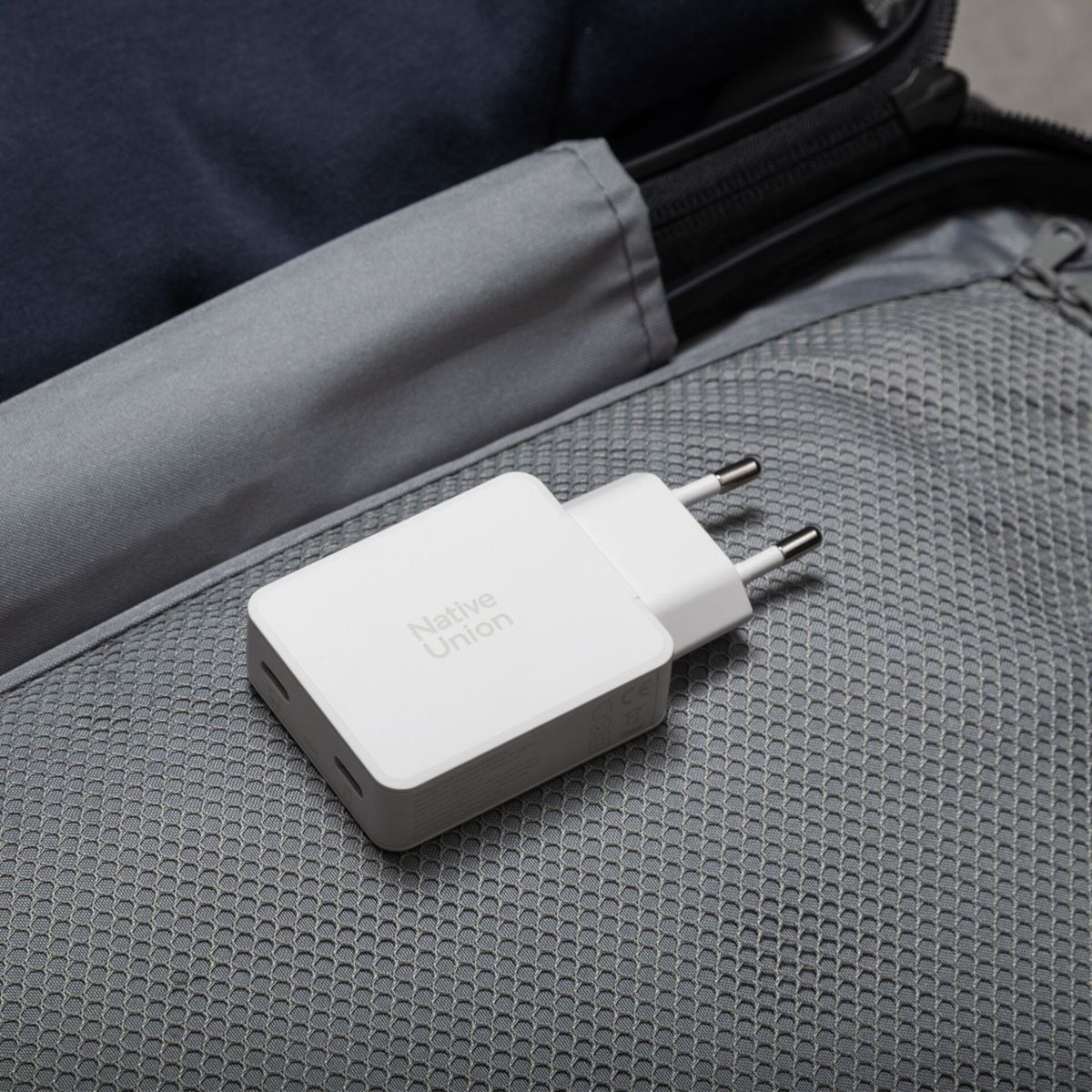 Ein weier Netzstecker mit zwei Pins liegt auf grauem Netzstoff.