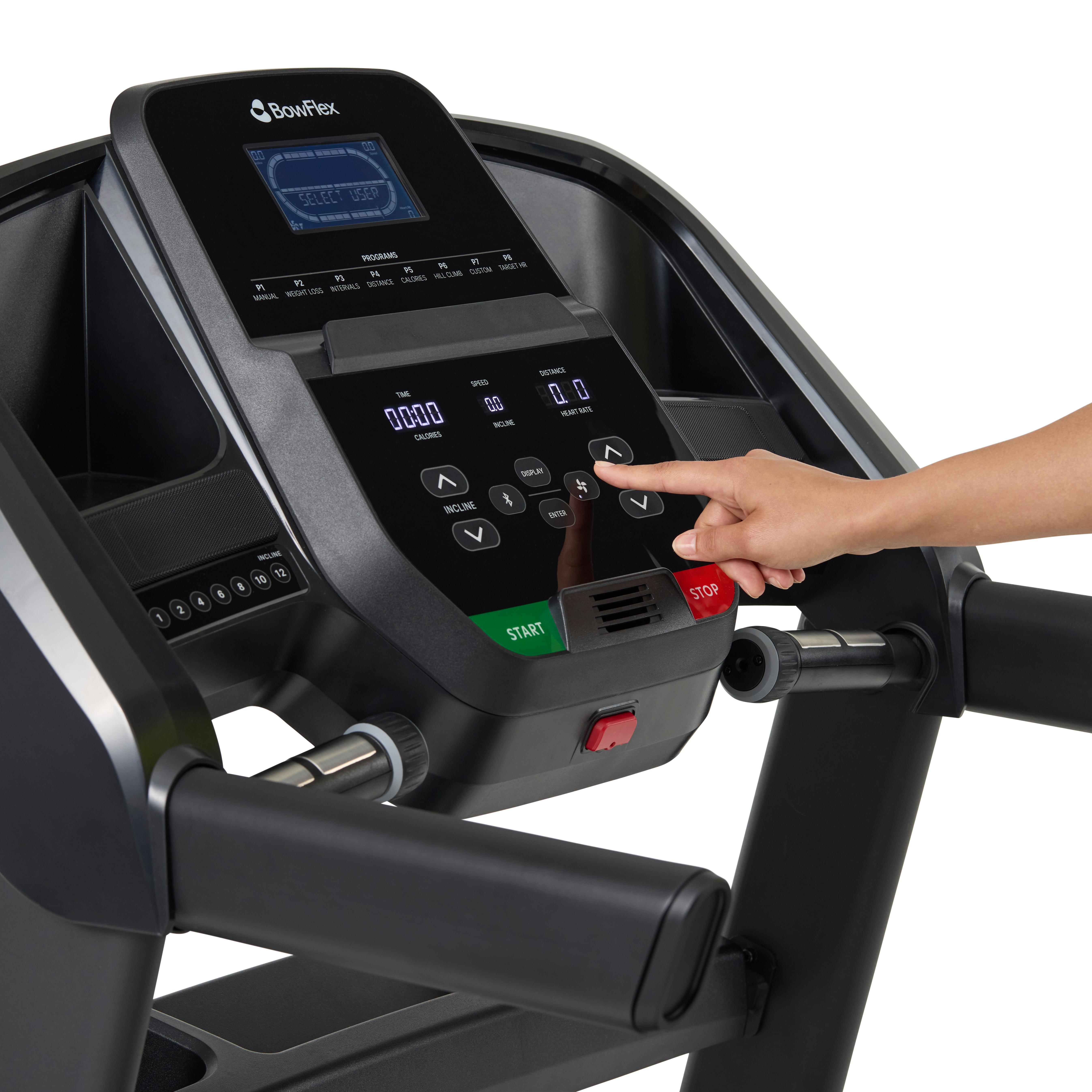 A finger presses an arrow button on a treadmill's control panel.