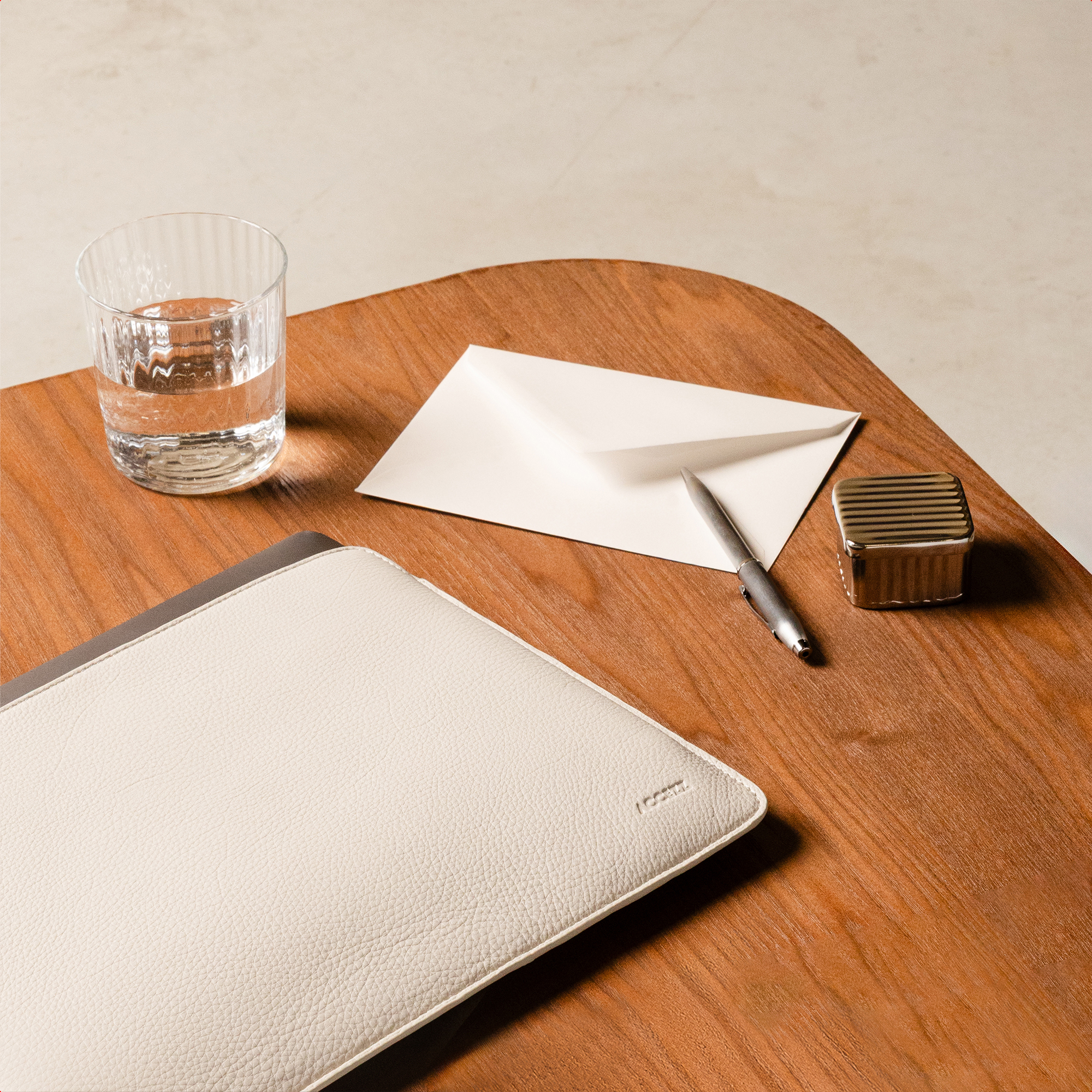 Een glas water, envelop, pen en hoes op een houten tafel.