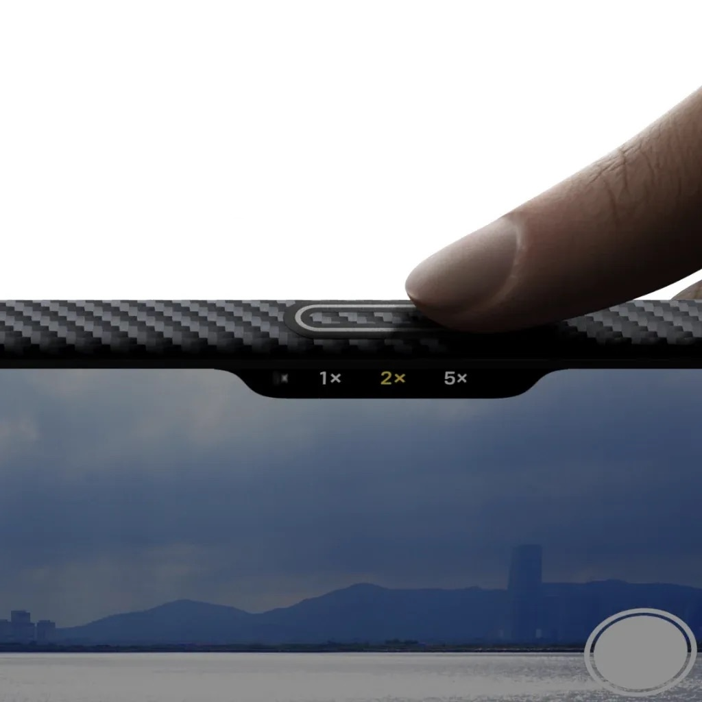Un dito tocca il controllo zoom 2x su un telefono con motivo in carbonio.