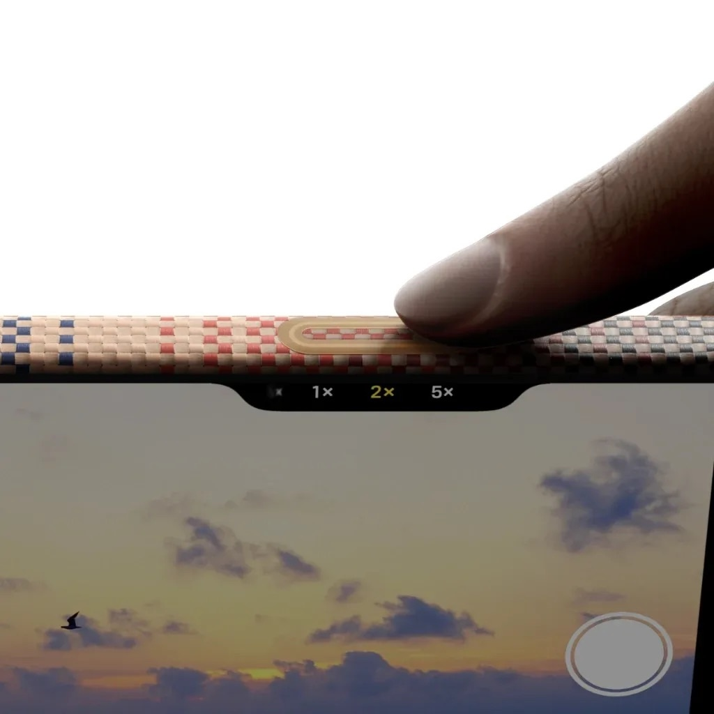 Un dito preme i pulsanti dello zoom della fotocamera di un telefono. Lo schermo mostra un tramonto e un uccello.