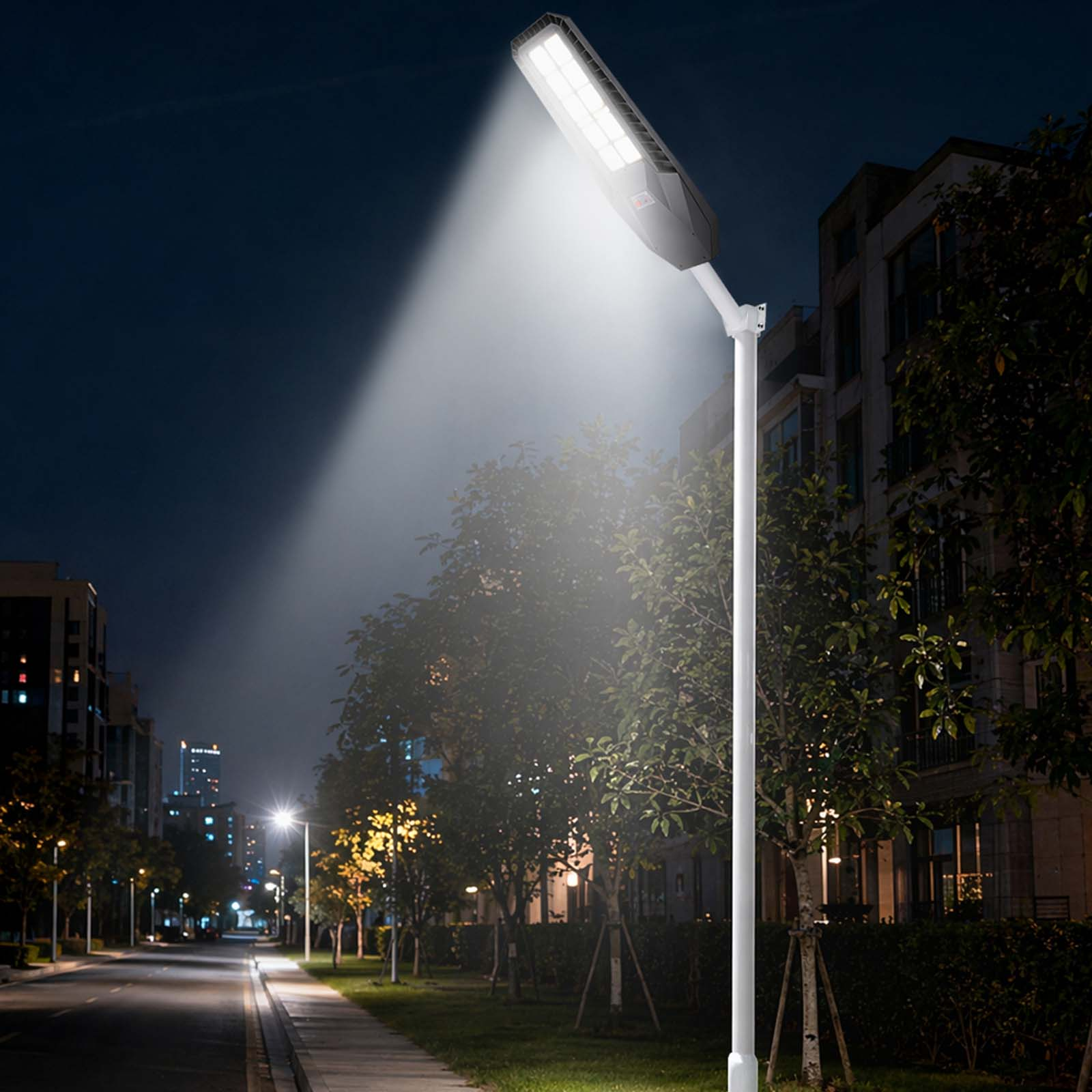 Moderne Straßenlaterne beleuchtet eine dunkle Straße mit Bäumen und Gebäuden.