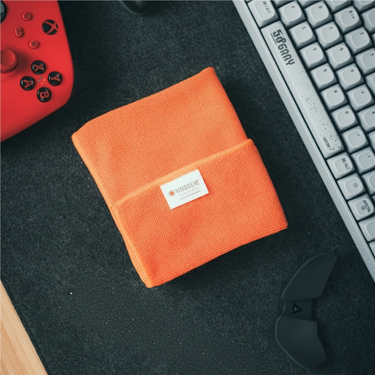 Een oranje microvezeldoek ligt naast een toetsenbord en een rode controller.