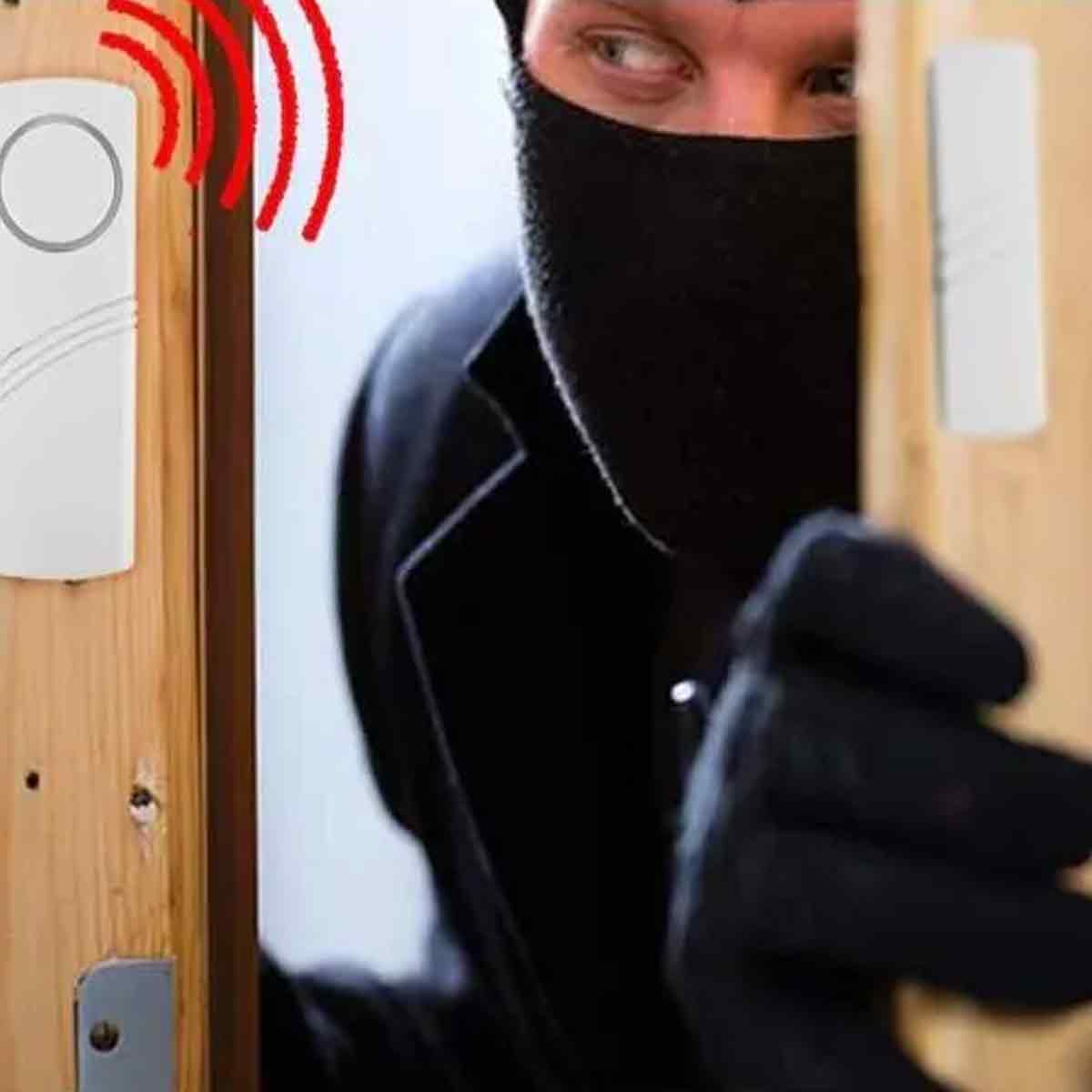 Ein Mann mit schwarzer Maske und Handschuhen versucht, eine Tür zu öffnen.