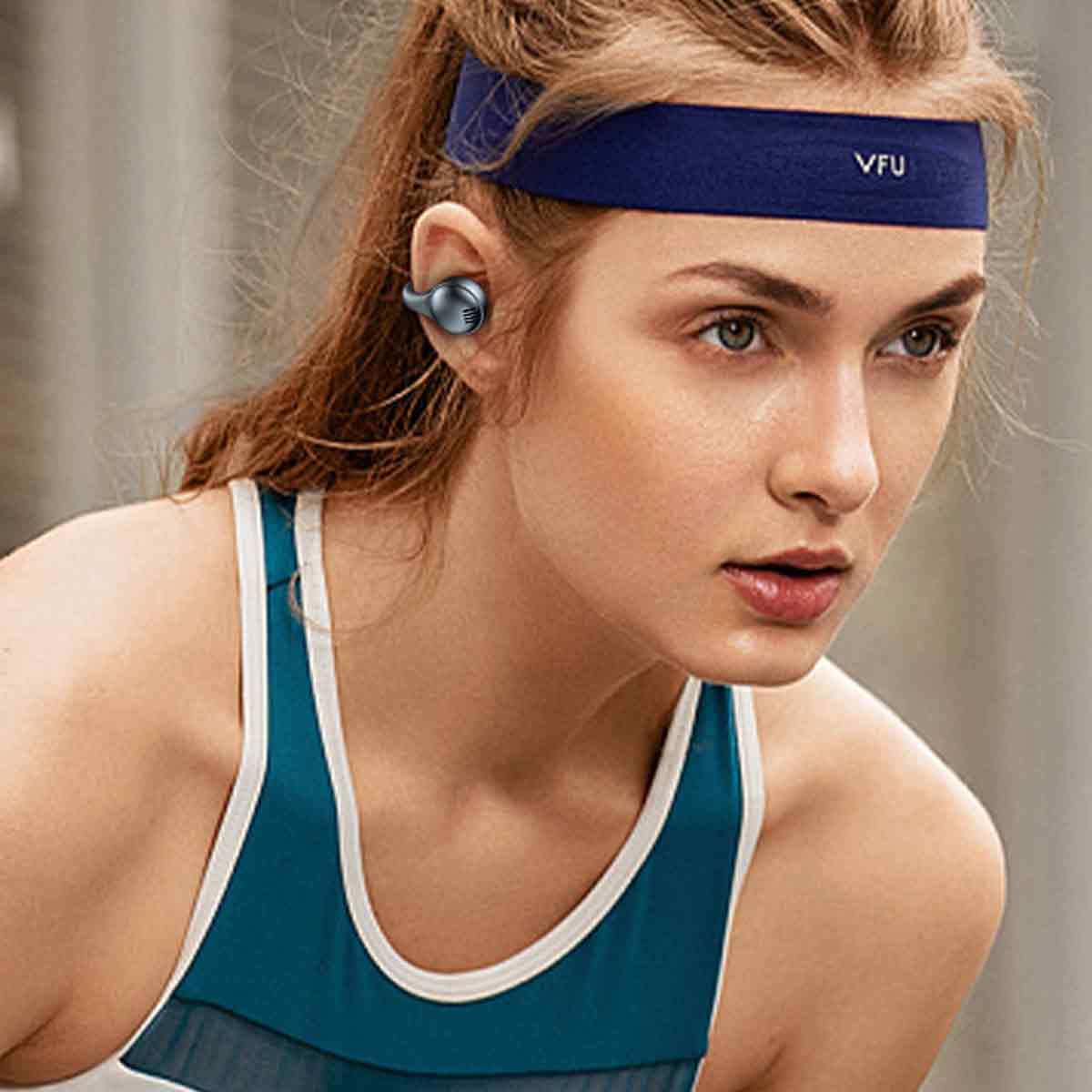 Junge Frau mit Stirnband und Ohrhörern, trägt Sportoberteil.