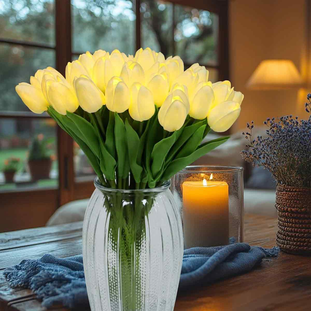 Ein Strauß beleuchteter gelber Tulpen in einer Glasvase auf einem Tisch.