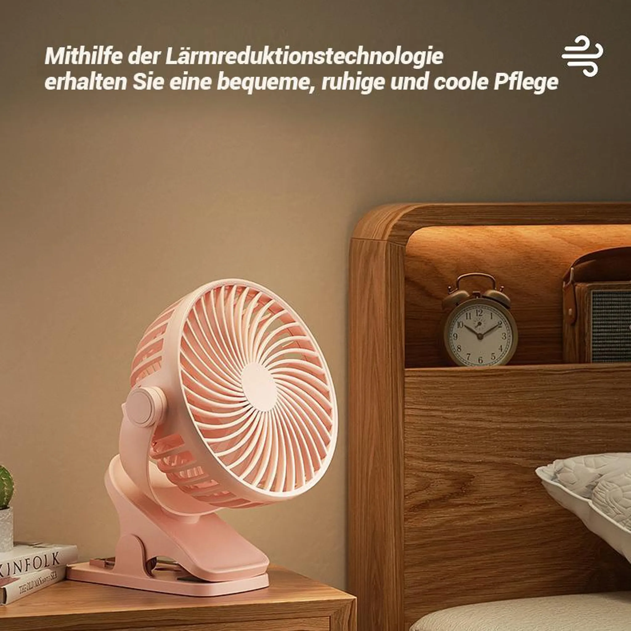 Ein rosafarbener Ventilator steht auf einem Nachttisch neben einem Bett. Ein Wecker ist im Regal.