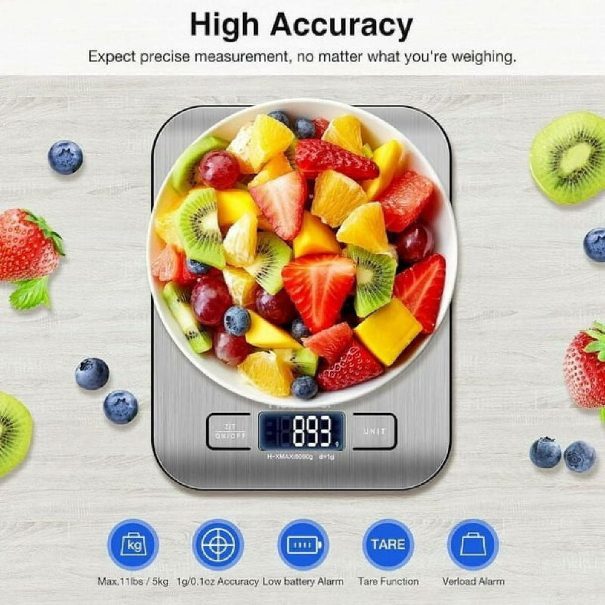 Eine digitale Küchenwaage mit Obstschale und Früchten wie Erdbeeren und Kiwis.