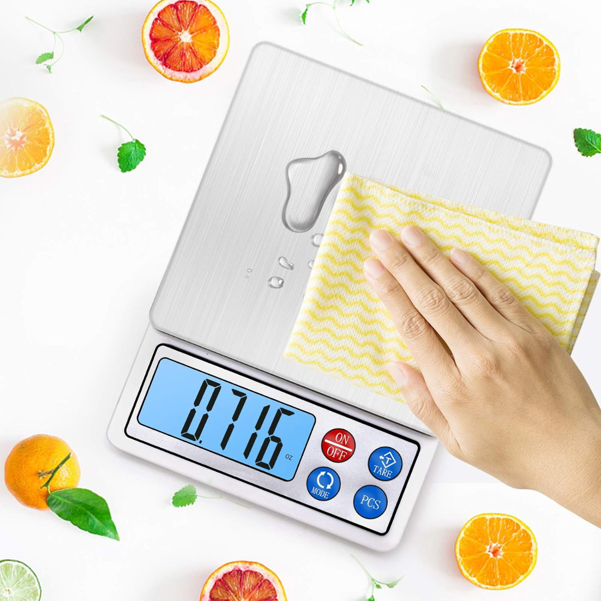 Eine Hand wischt eine digitale Küchenwaage mit gelbem Tuch ab, um Wasserflecken zu entfernen.