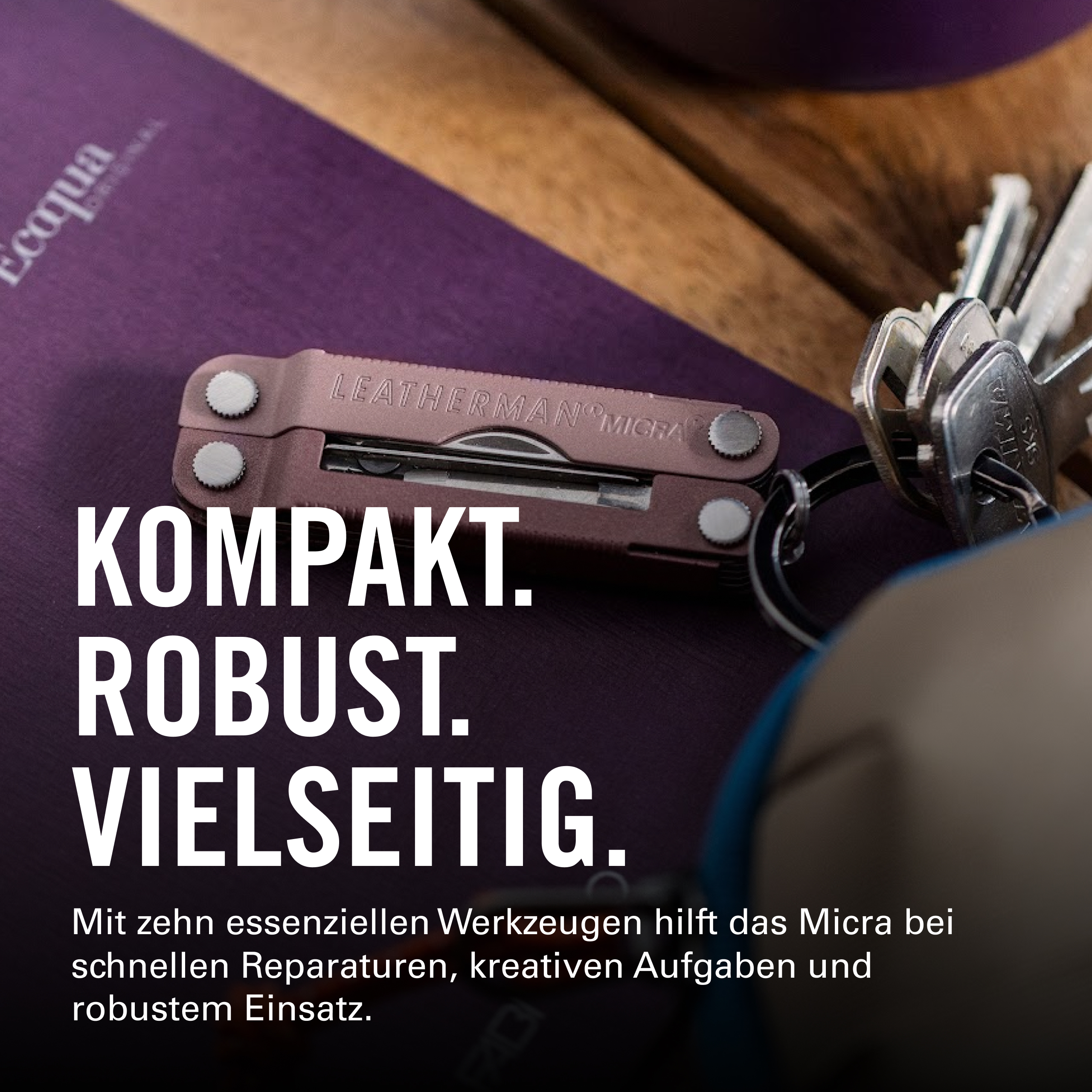 Ein rosafarbenes Leatherman Micra Multitool mit Schlüsseln auf einem Holztisch.