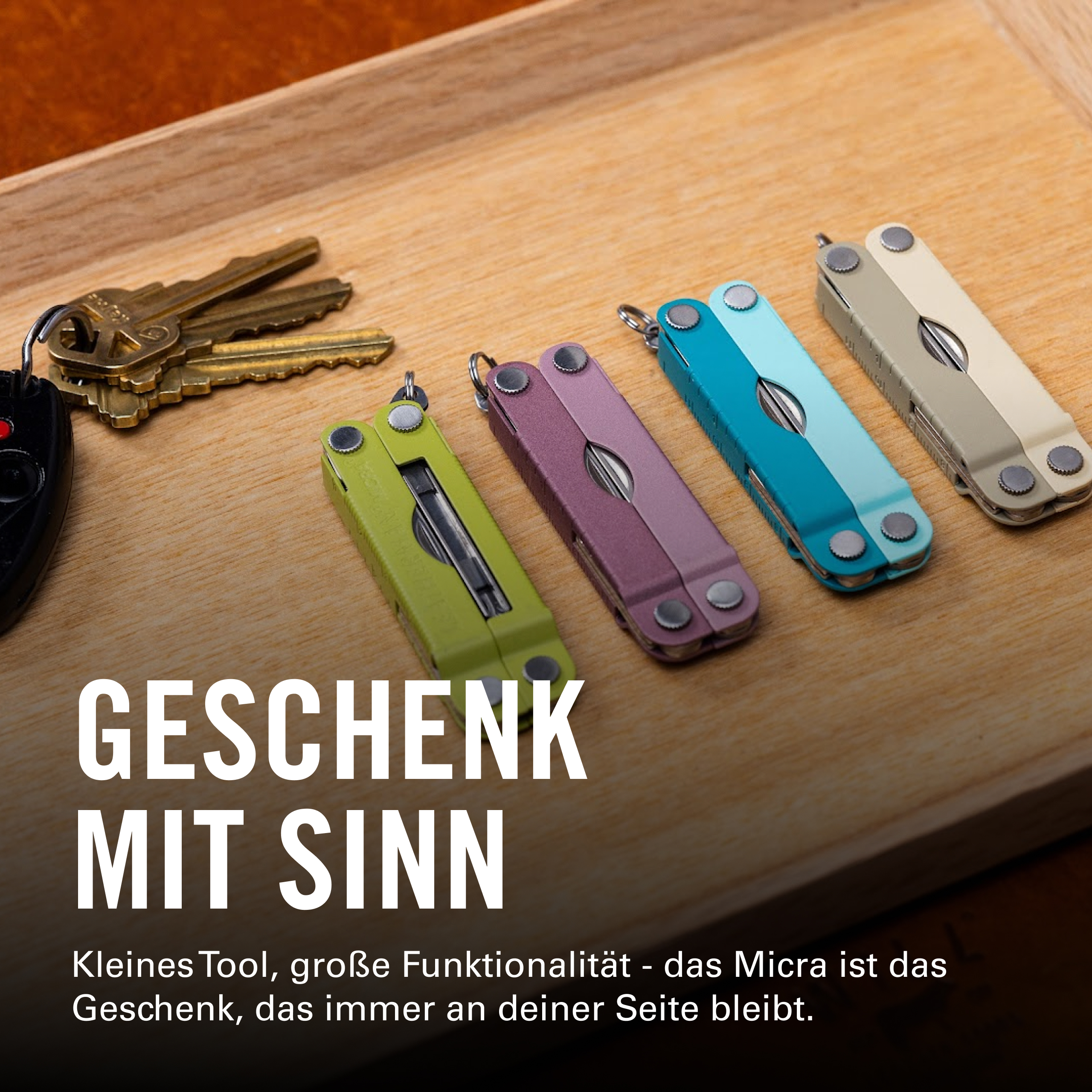 Vier bunte Multitools und Schlüssel auf einem Holztablett.