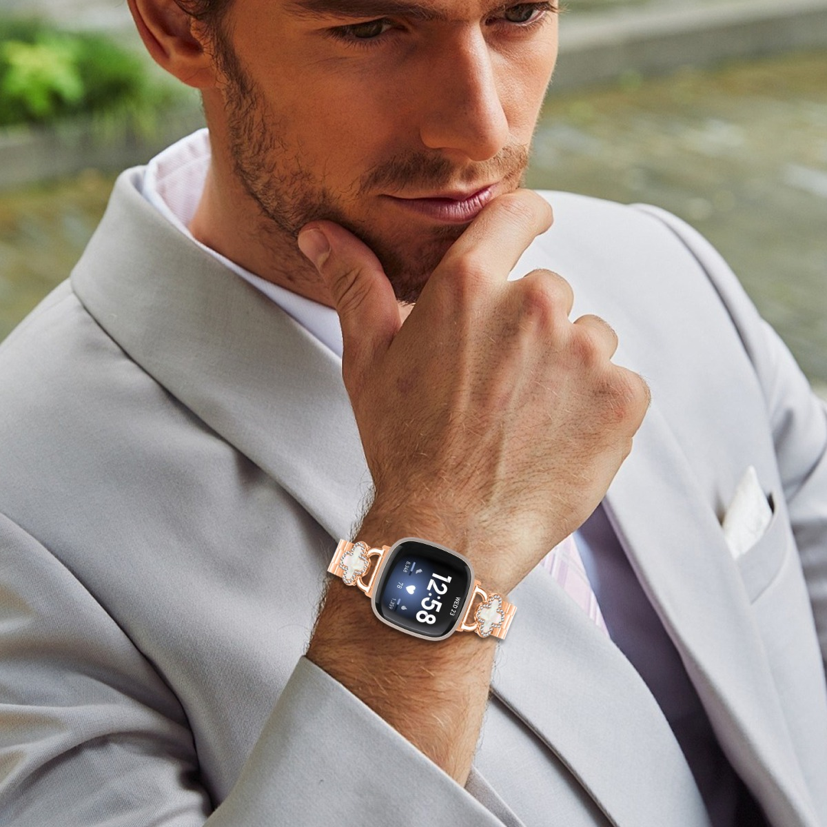 Ein Mann im grauen Anzug trägt eine Smartwatch mit einem funkelnden Armband.
