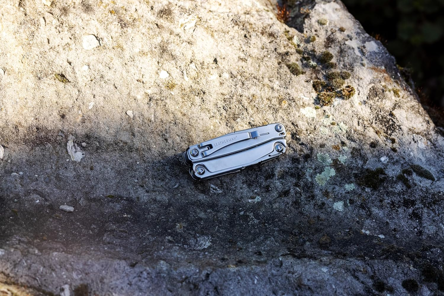 Ein silbernes Leatherman-Multitool liegt auf einem bemoosten Felsen.