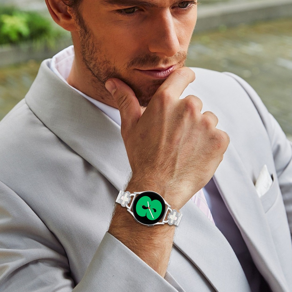 Ein Mann in einem grauen Anzug trägt eine Smartwatch mit einem grünen Zifferblatt.