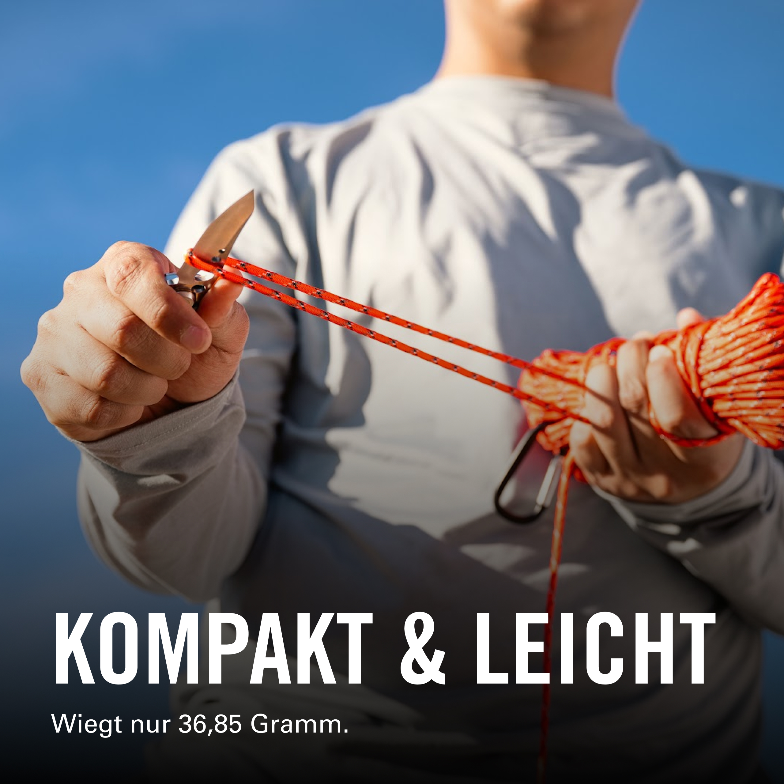 Mann hält ein Messer und eine rote Schnur vor blauem Himmel.