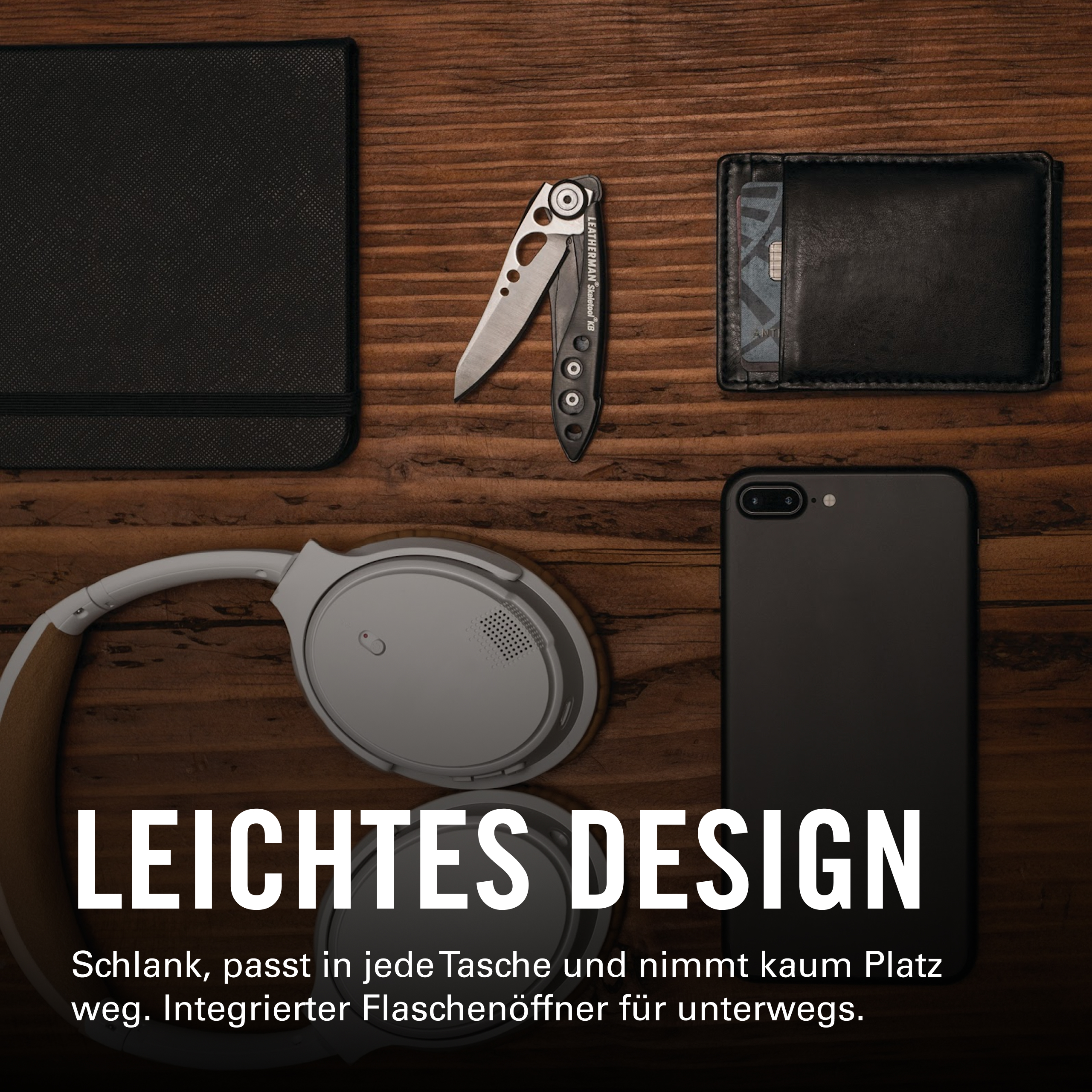 Schwarzes Notizbuch, Messer, Portemonnaie, Kopfhörer und Smartphone auf Holz.