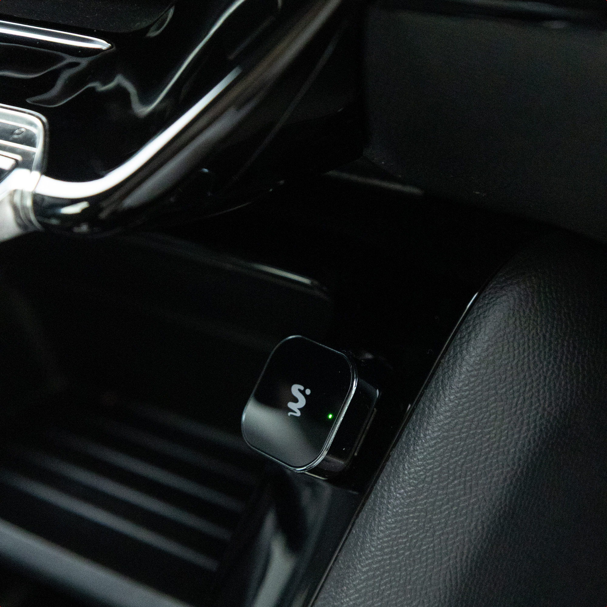 A black car cigarette lighter adapter with a green light.