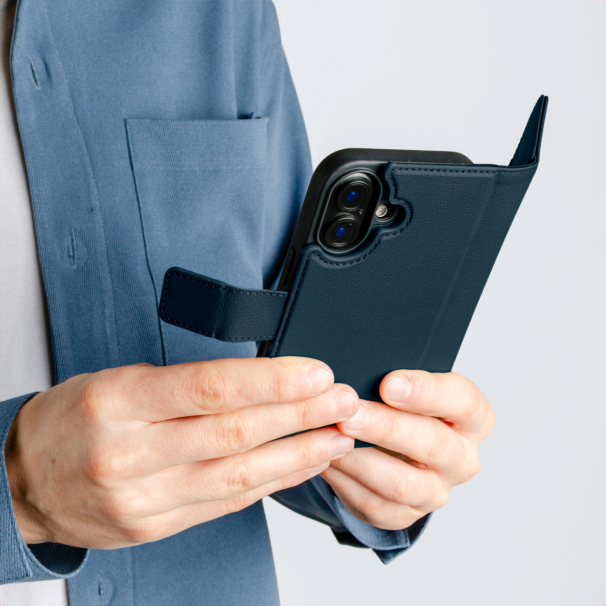 Eine Person in einem blauen Blazer hält ein dunkelblaues Handy mit Klapphülle.