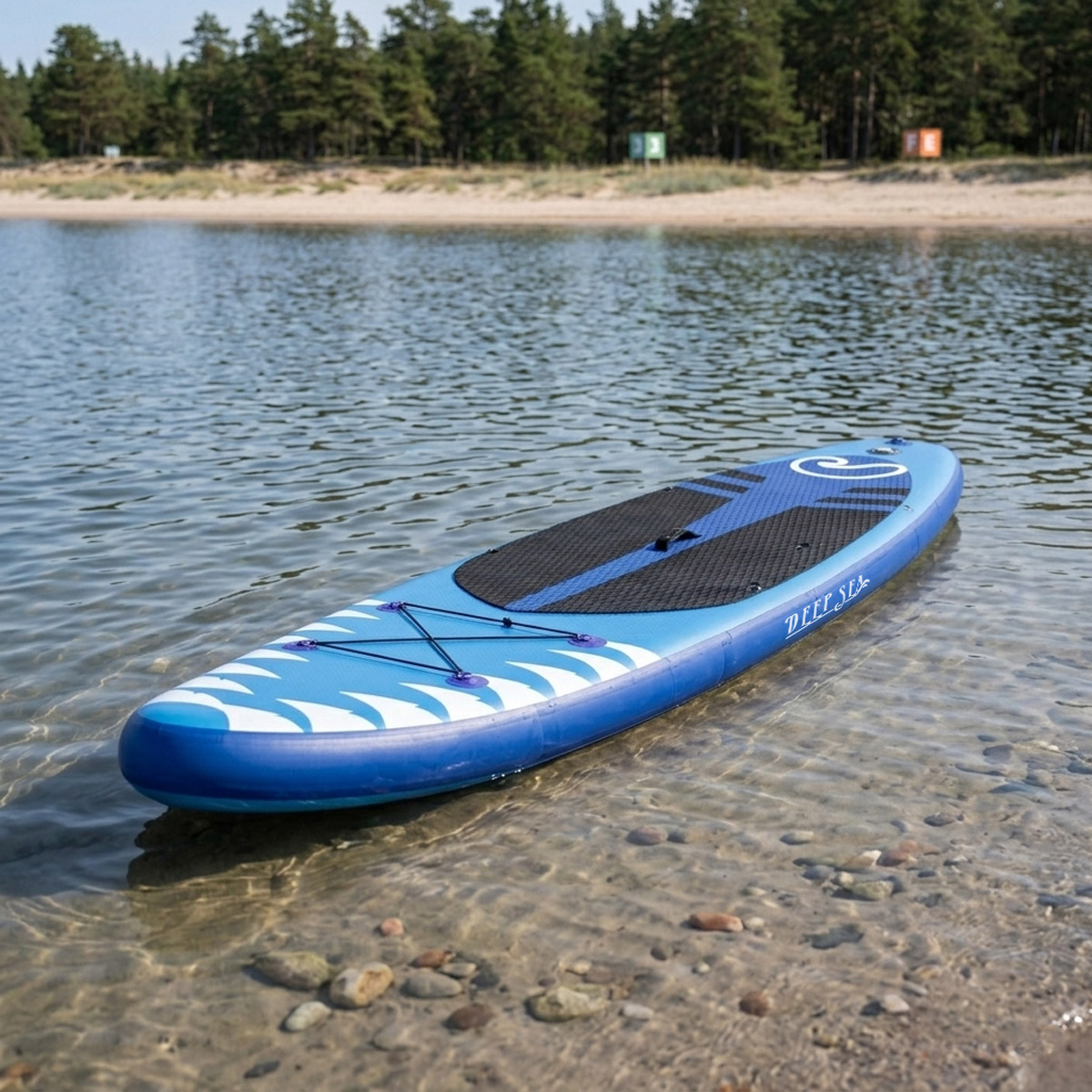 Ein blaues aufblasbares Stand-Up-Paddleboard ruht in flachem, klarem Wasser nahe einem Sandstrand.