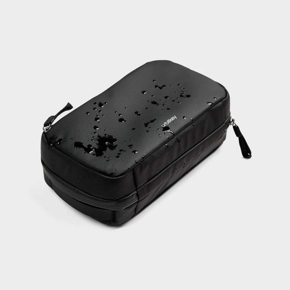 Czarny organizer Orbitkey z kroplami wody na szarym tle.