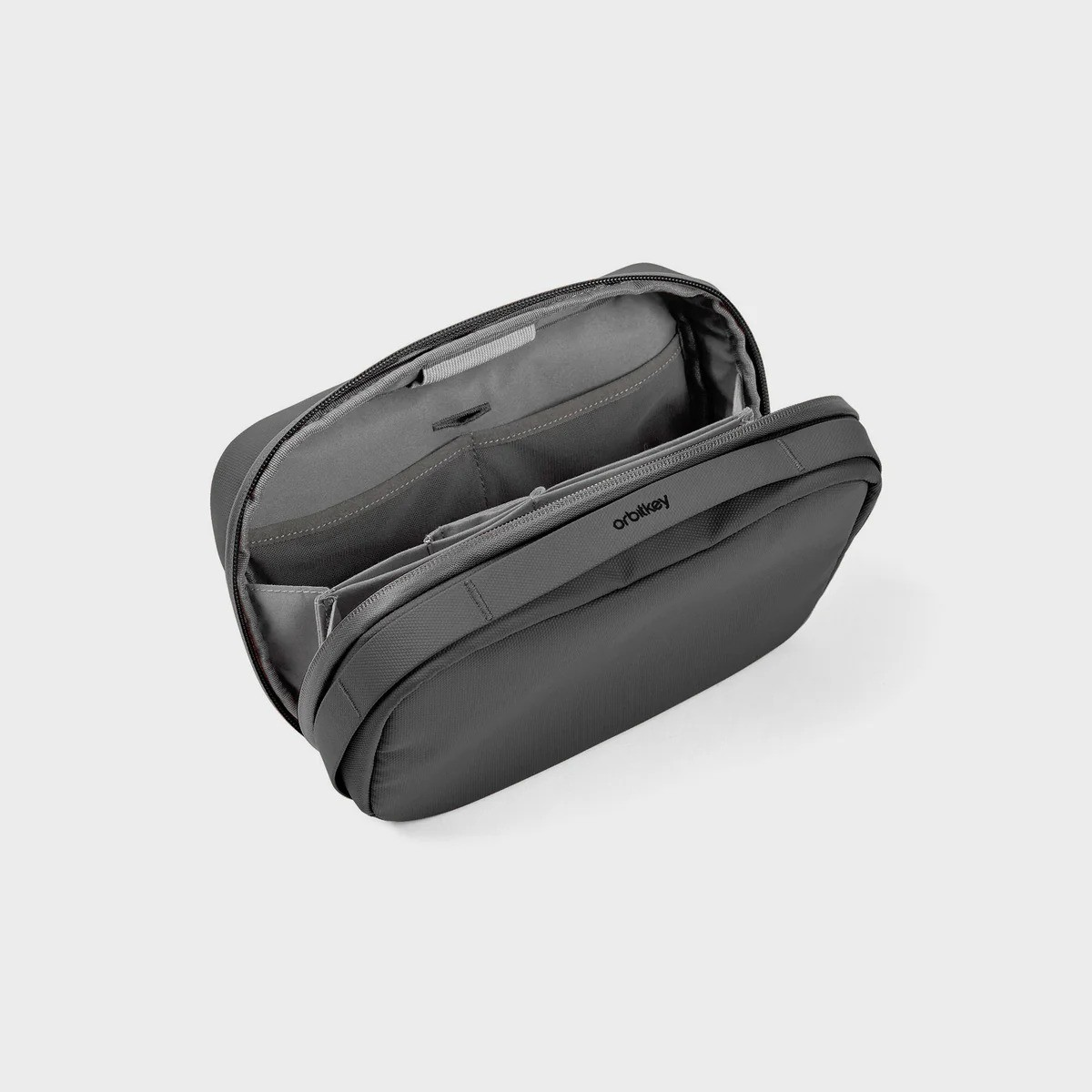 Otwarta ciemnoszara torba Orbitkey z wewnętrznymi kieszeniami na jasnoszarym tle.
