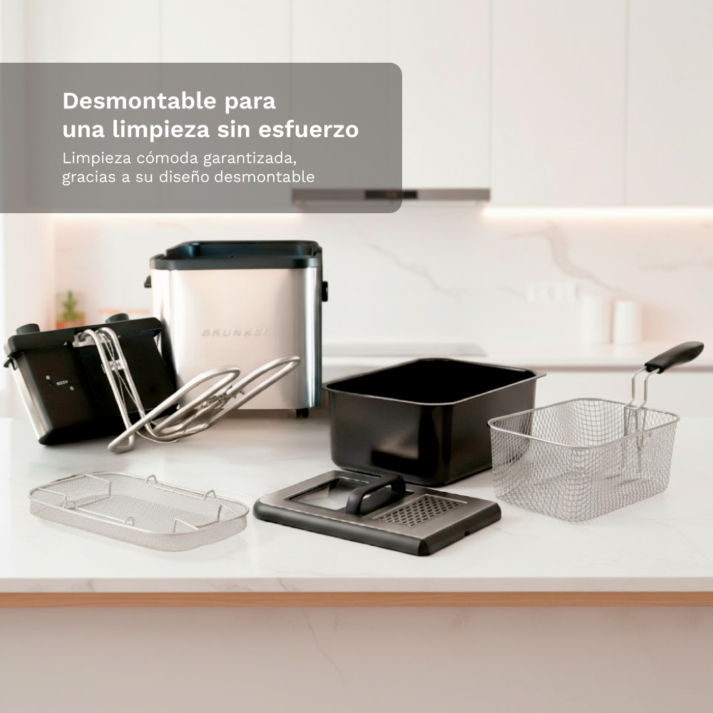 Partes de freidora desmontadas en encimera: cuerpo plateado, olla negra, cesta metálica.
